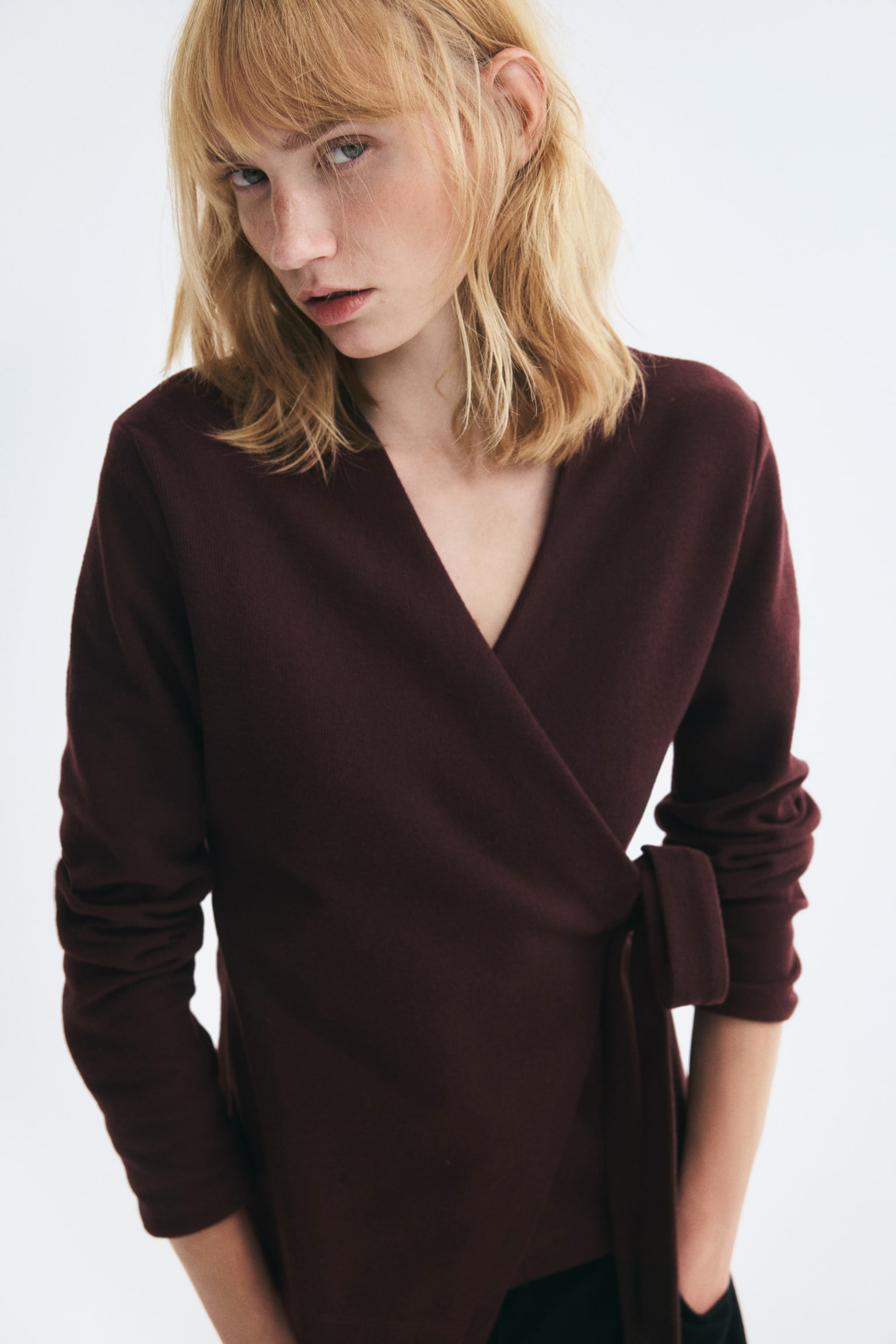 Un cardigan cache-cÅur en maille douce, de couleur bordeaux foncÃ©, prÃ©sentÃ© de face, avec un col en V et des manches longues. Le modÃ¨le se ferme sur un cÃ´tÃ© Ã  lâaide de larges liens en tissu nouÃ©s en nÅud. - 1