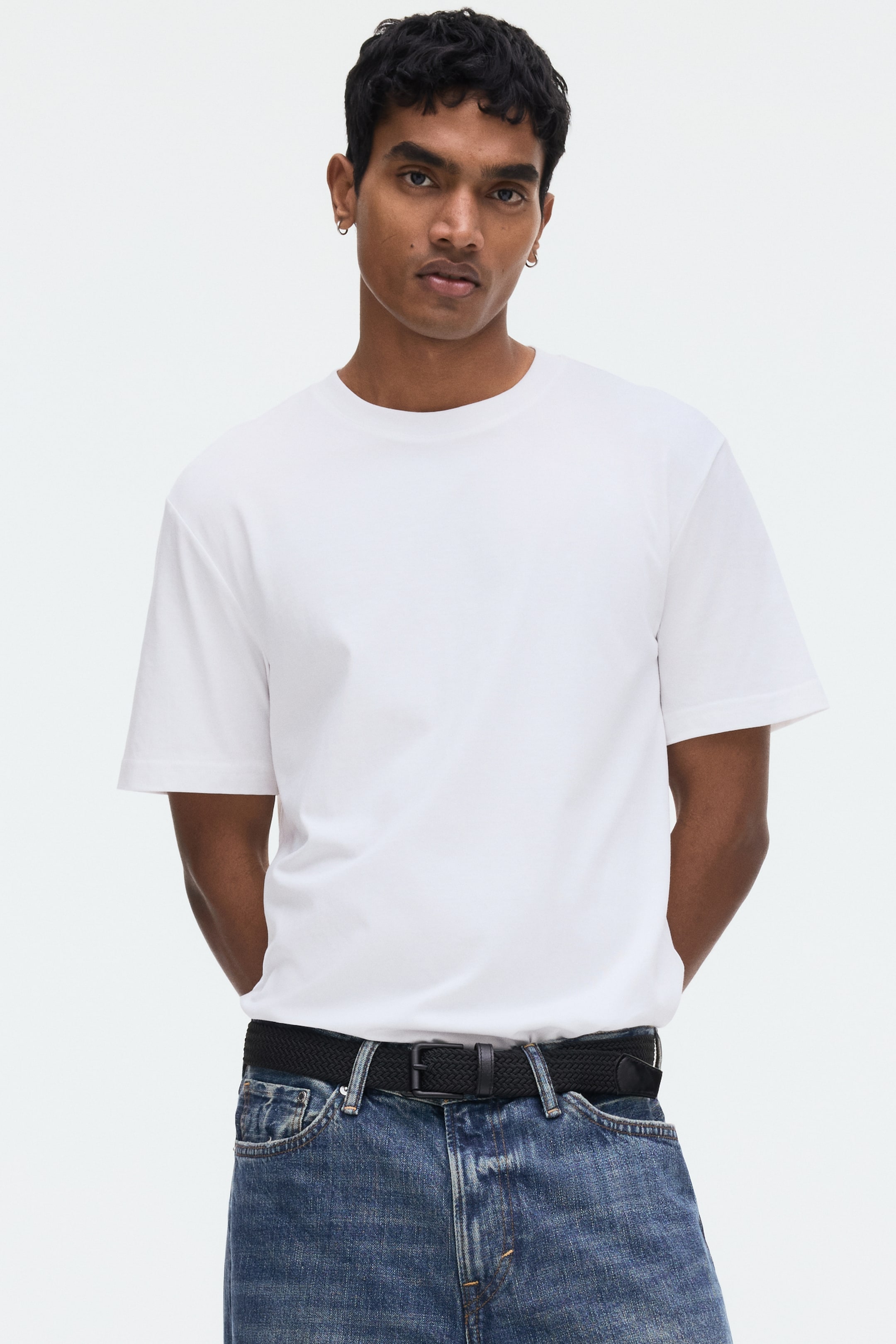 Ingrandisci l'immagine: Una t-shirt bianca a girocollo è indossata in vista frontale, caratterizzata da maniche corte e una vestibilità comoda, infilata nei jeans.