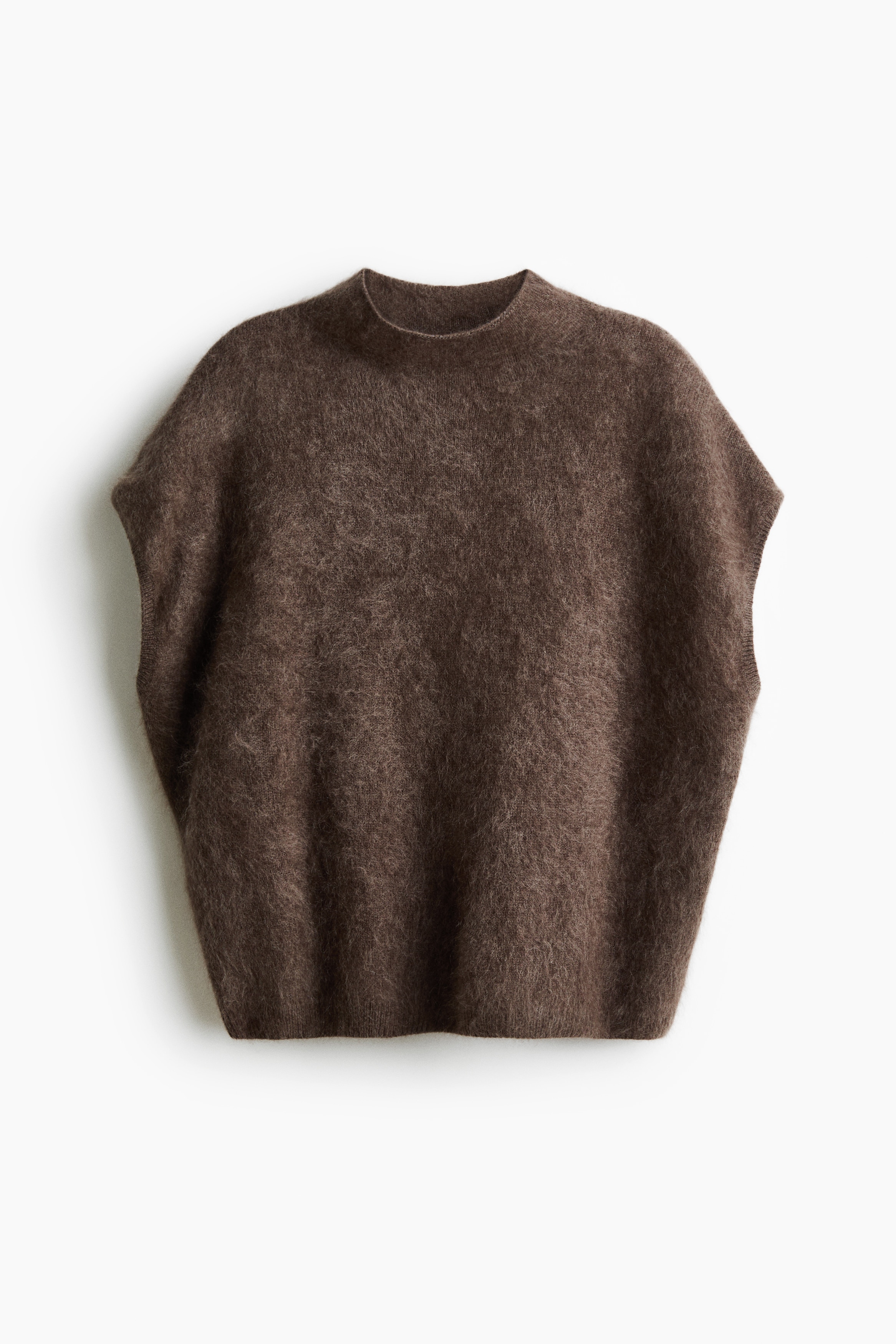 A brown, fuzzy knitted wool vest featuring a high neck and ribbed details around the armhole is being worn by the model. The oversized vest showcases a soft, textured finish as the model turns slightly to the side.