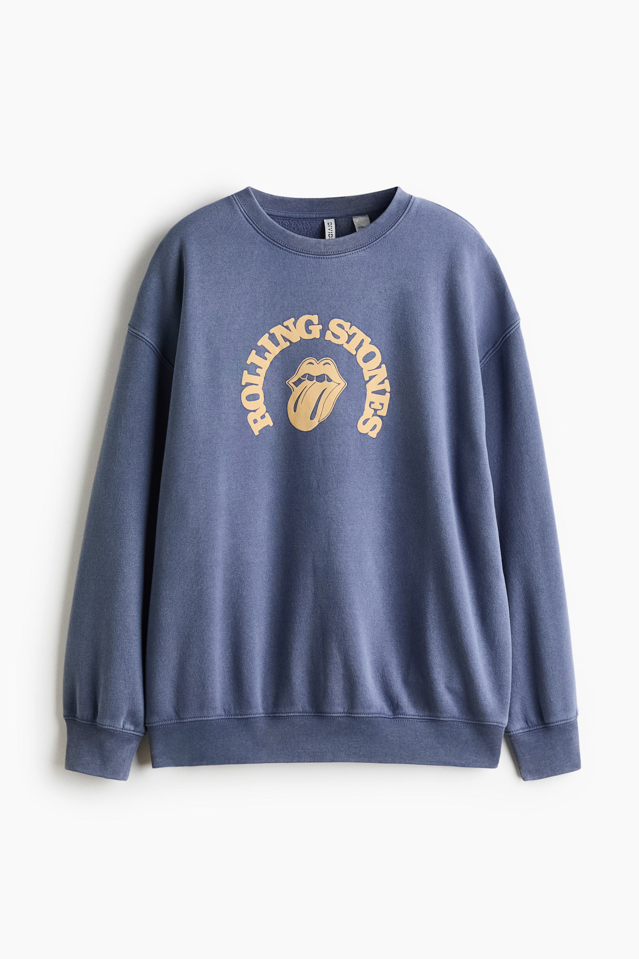 View larger image: An oversized blue sweatshirt is shown from the front, featuring a ribbed crew neck, dropped shoulders, and a printed yellow graphic of the Rolling Stones tongue logo on the chest. The garment has long sleeves with ribbed cuffs and a matching ribbed hem.