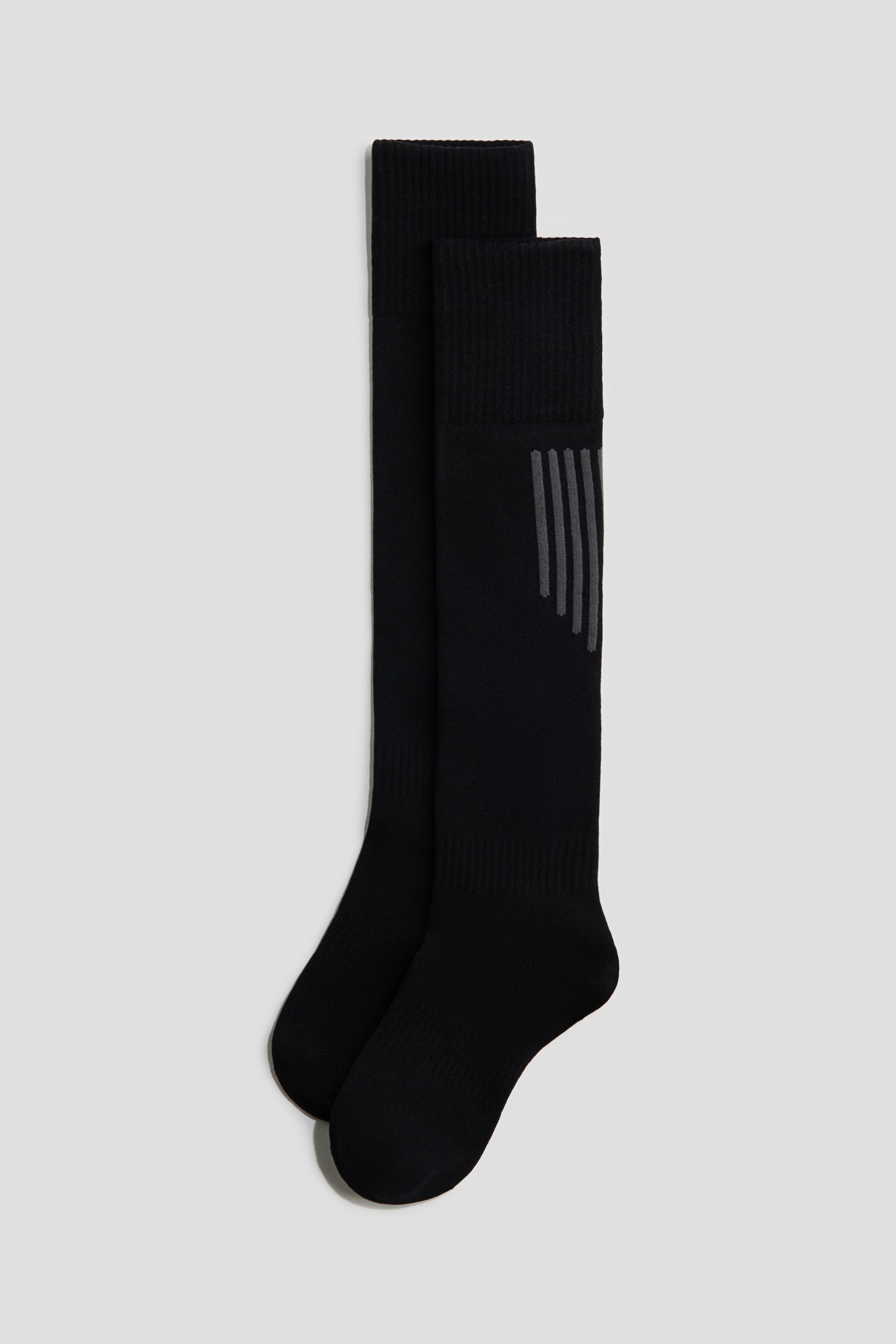 View larger image: A pair of black knee-high socks showcases ribbed cuffs. The front sock features multiple angled grey stripes on its outer calf.