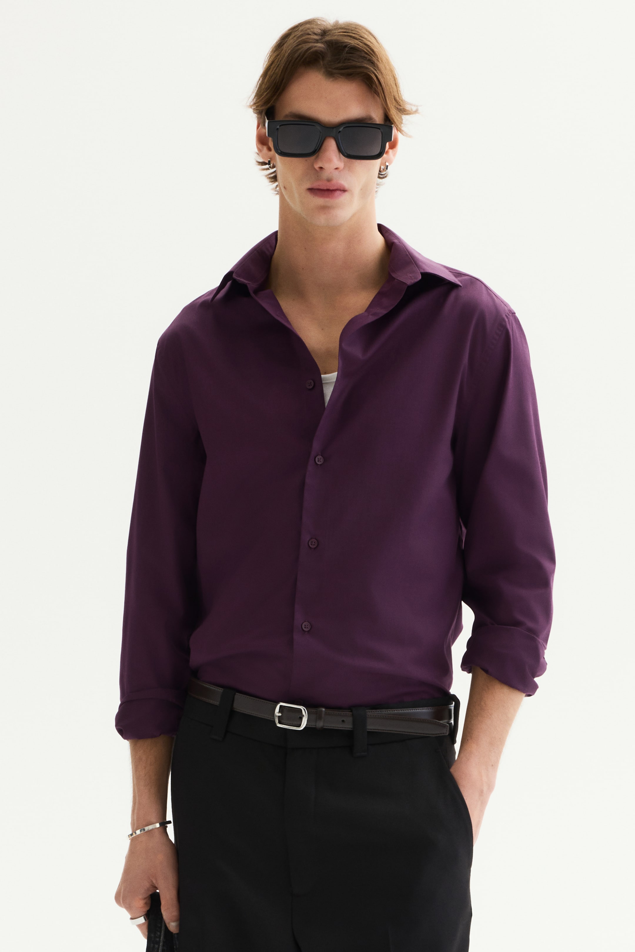 View larger image: The deep purple long-sleeved shirt showcases a spread collar, with the top two buttons left open over a white undershirt. Its long sleeves are rolled up above the wrists.