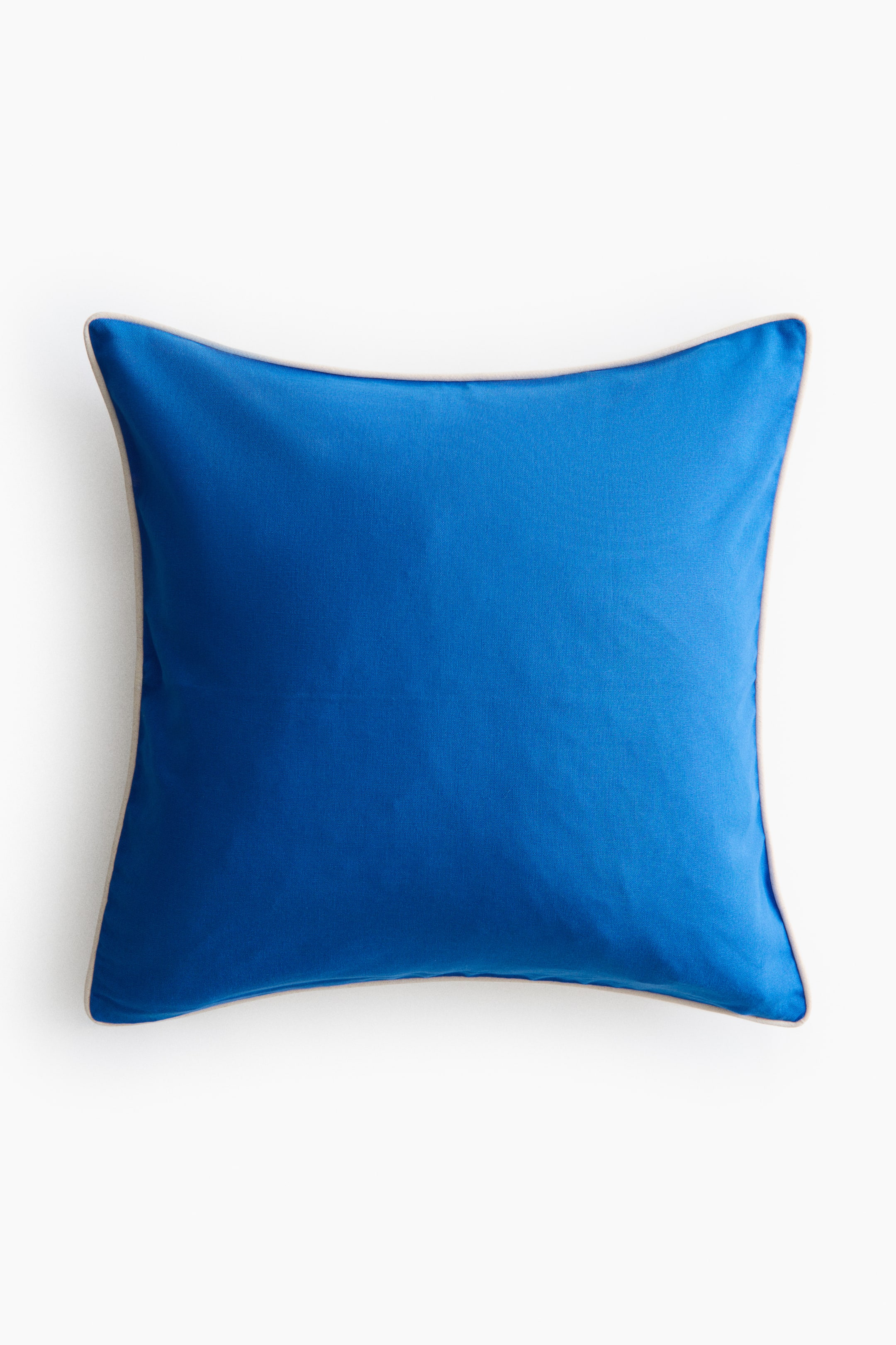 Voir une image plus grande: Une housse de coussin en toile de coton affiche son AVANT, présentant une surface d'un bleu vif. Un passepoil étroit, de couleur claire, court le long de tous ses bords.