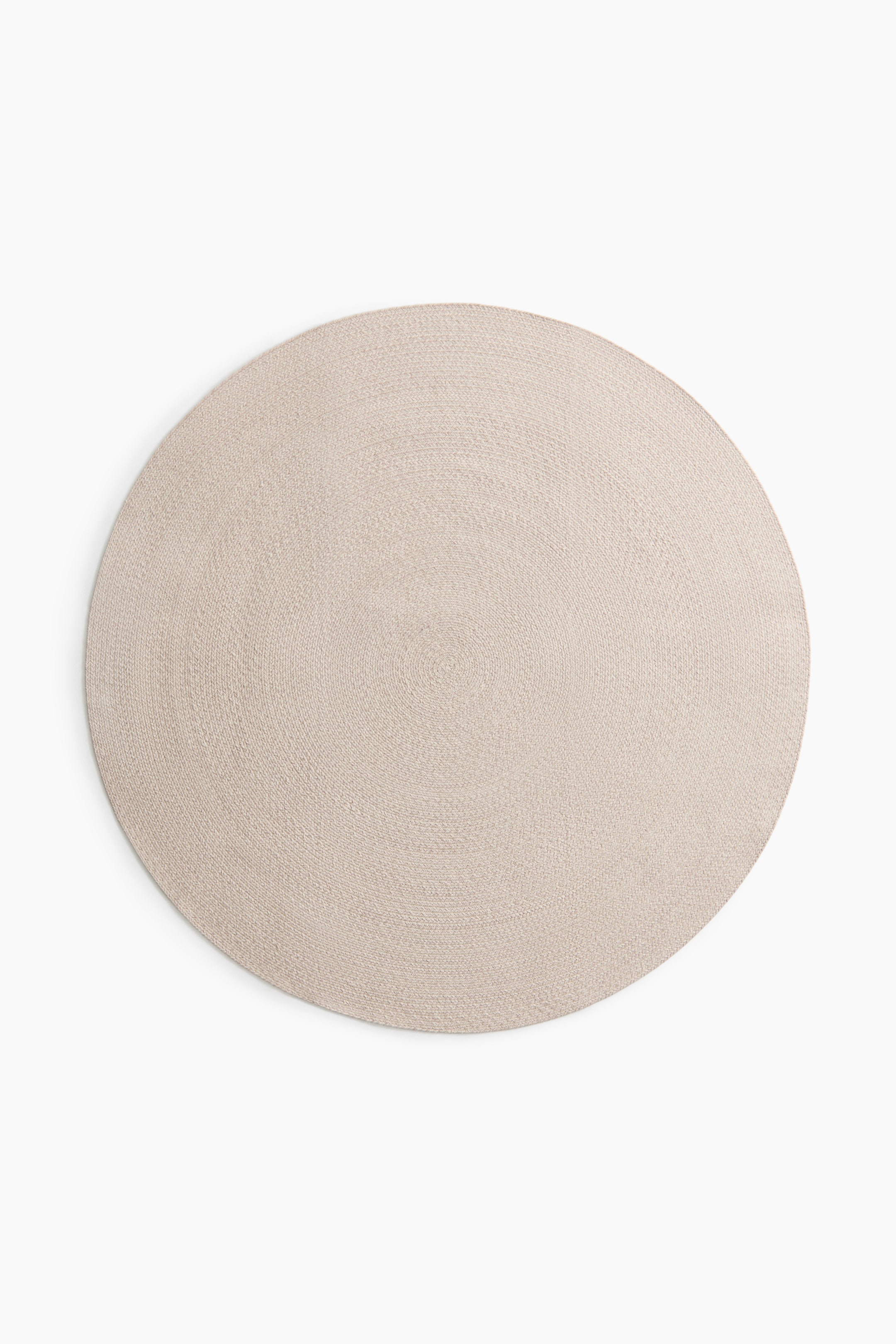 View larger image: A round mat in light beige, showcasing a woven texture with concentric circles spiralling from its centre.
