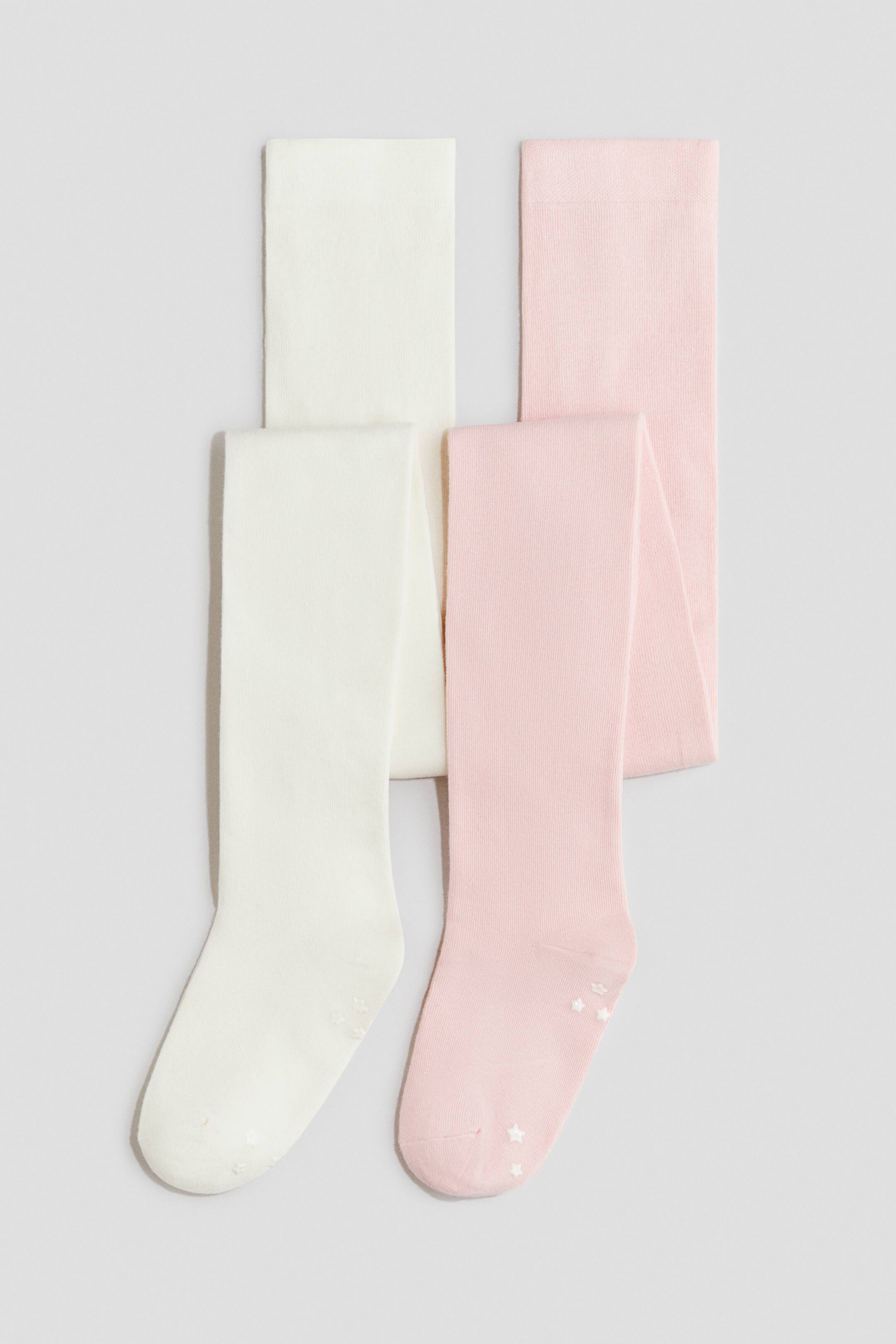 Agrandir l'image: Deux paires de collants en maille sont présentées pliées, l’une en blanc cassé et l’autre en rose clair. La paire blanc cassé présente des picots antidérapants en forme de points, tandis que la paire rose affiche des picots antidérapants en forme d’étoiles sur les semelles.