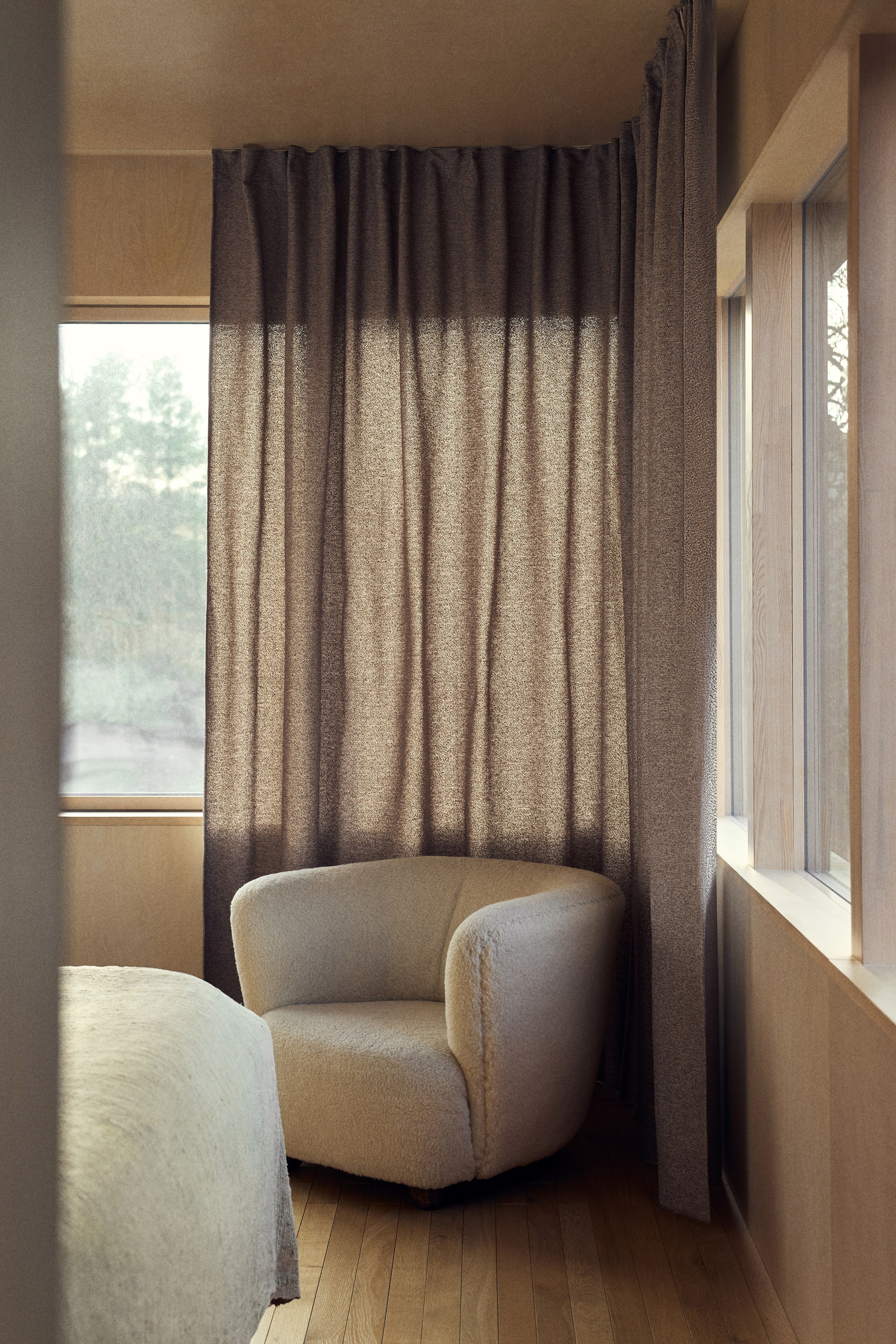 Grösseres Bild ansehen: Ein Sessel mit abgerundetem Rücken und Armlehnen, bezogen mit einem cremefarbenen Bouclé-Stoff. Er präsentiert sich in einem flachen Design, das so ausgerichtet ist, dass es seine Vorder- und Seitenansichten zur Geltung bringt.