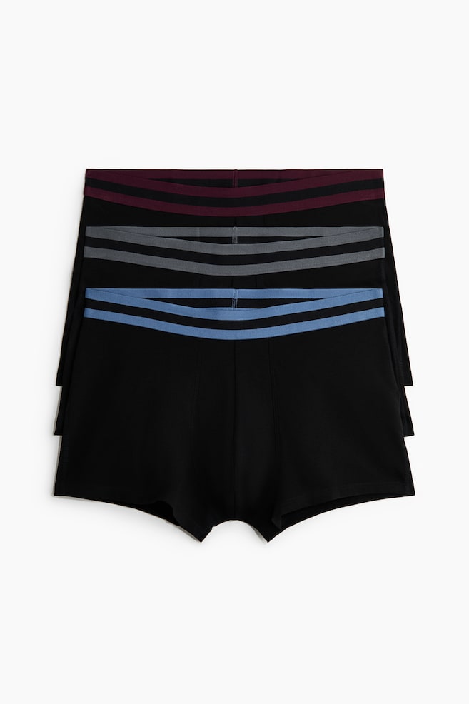 Drei schwarze Boxershorts liegen gestapelt, nach vorne gerichtet. Jede Shorts verfügt über einen elastischen Bund mit zwei horizontalen schwarzen Streifen. Der obere Bund ist burgunderrot, der mittlere grau und der untere hellblau. - 1