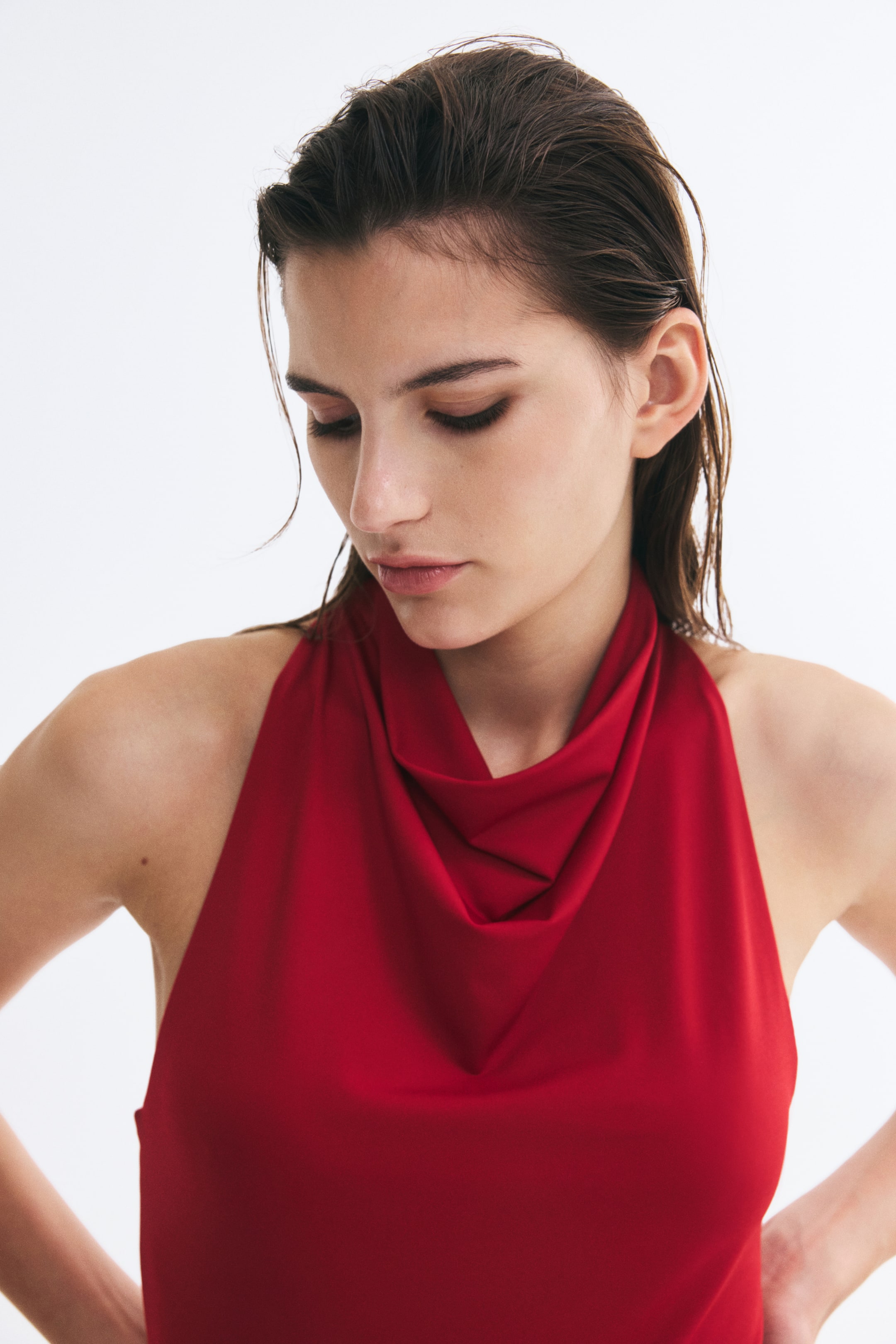 Ampliar la imagen: La modelo lleva un body rojo sin mangas con cuello drapeado tipo cowl y un corte estrecho en los hombros.