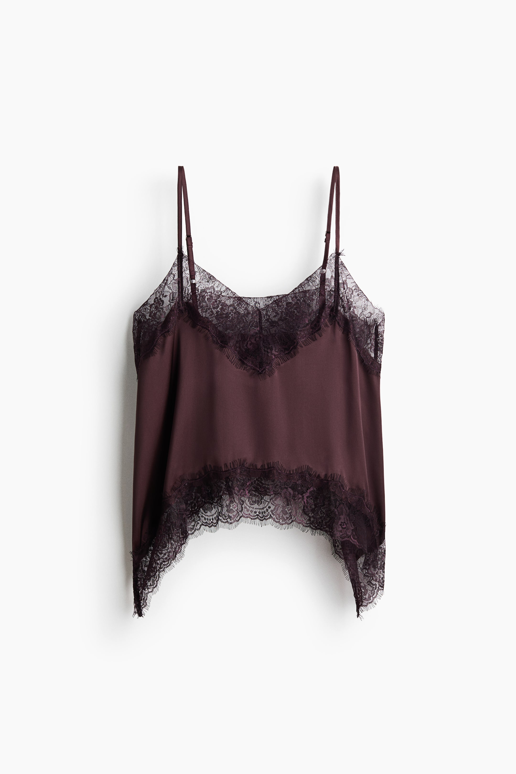 View larger image: A short, dark plum satin top is shown from the front, featuring a V-neckline trimmed with delicate eyelash lace and narrow, adjustable shoulder straps. The top drapes softly, showcasing an arched hemline finished with a matching wide lace border.