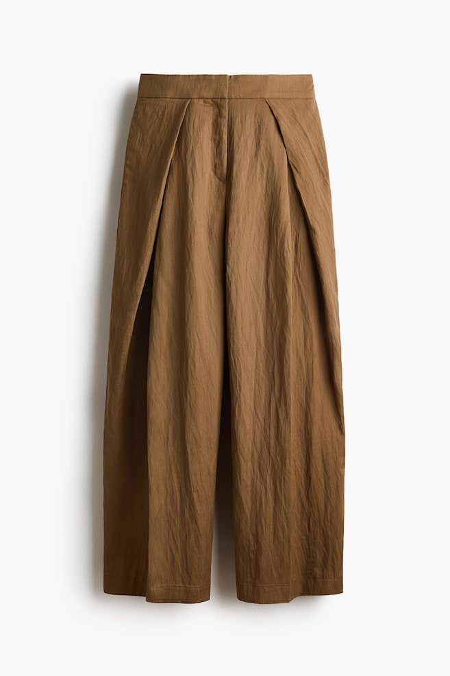 Brown wide-leg trousers boast a crinkled texture, prominent front pleats, and a flat waistband with a discreet front fastening, showcasing a cropped length. - 1