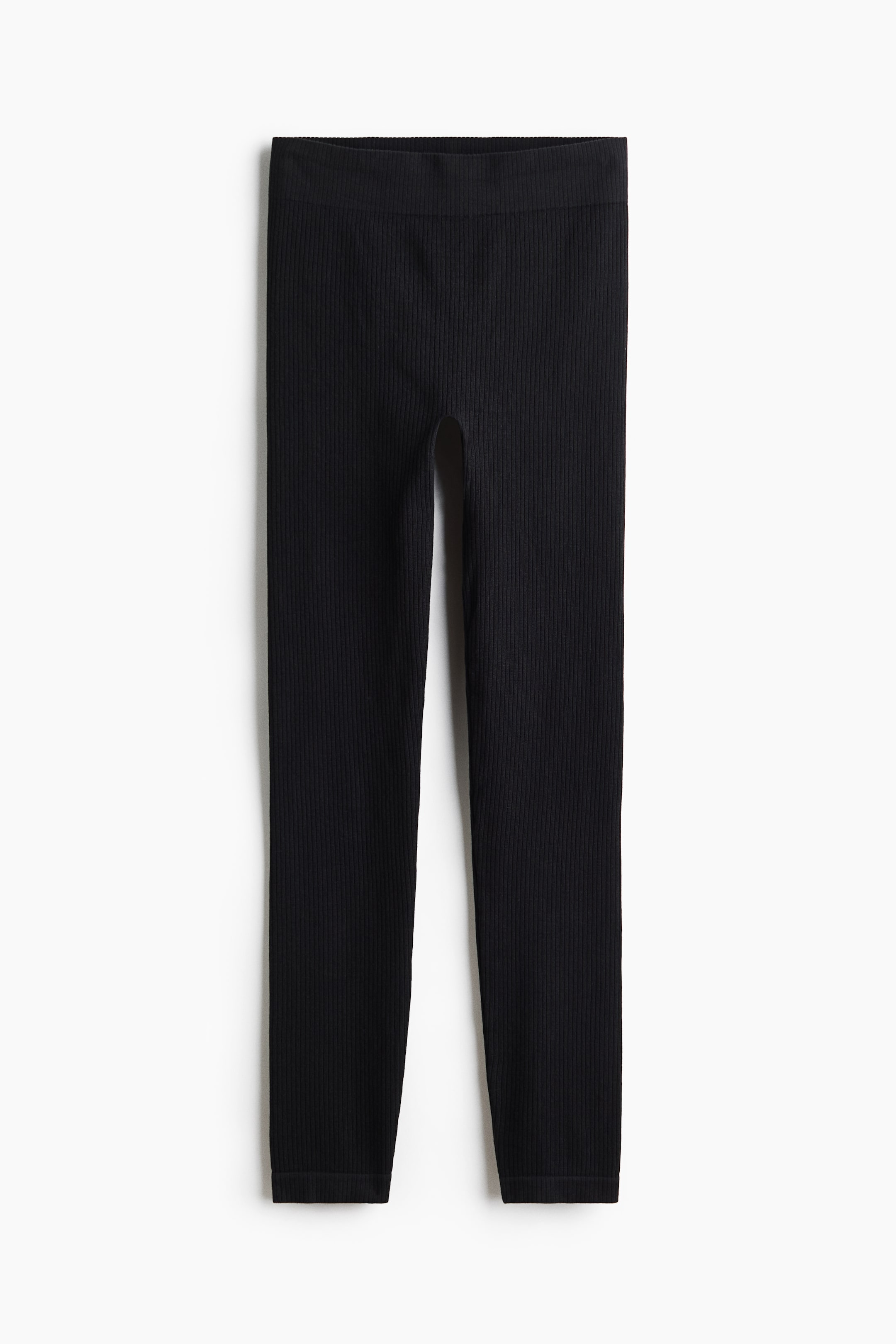 View larger image: Black rib-knit leggings are shown from the front, with a regular waist. They feature a smooth, seamless design along the legs.