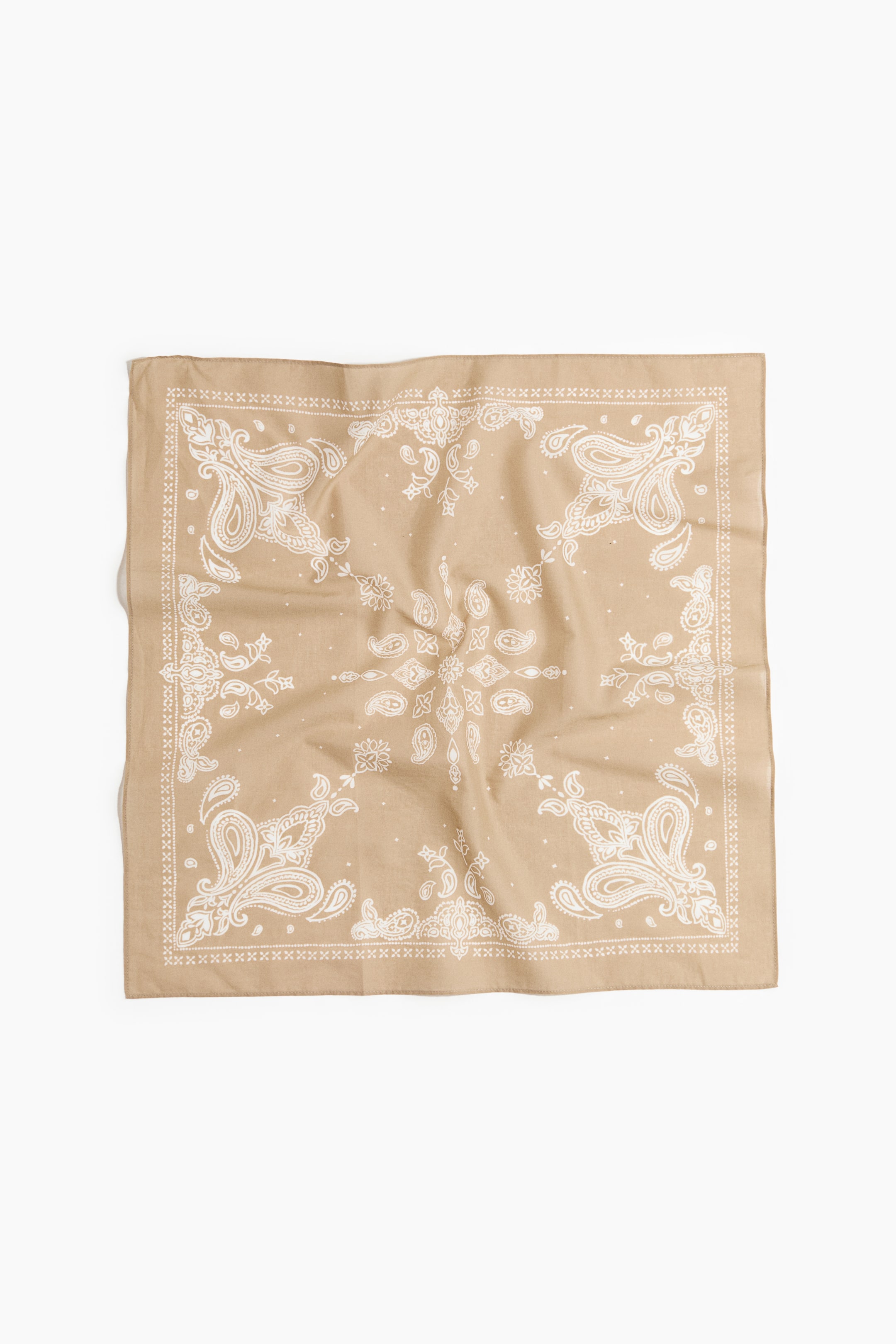 Grösseres Bild ansehen: Ein beigefarbenes Bandana liegt flach und zeigt ein weißes Paisleymuster auf der gesamten Oberfläche sowie einen dekorativen Rand aus weißen X-Mustern und Punkten entlang der Kanten. Es ist leicht geknittert.