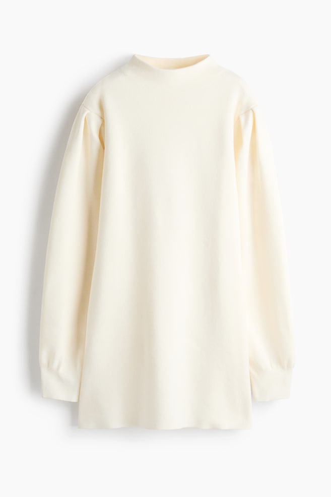 A cream-colored knit top is hanging facing the front, showcasing a mock neck, a relaxed silhouette, and long sleeves with puffed shoulders and ribbed cuffs. - 1
