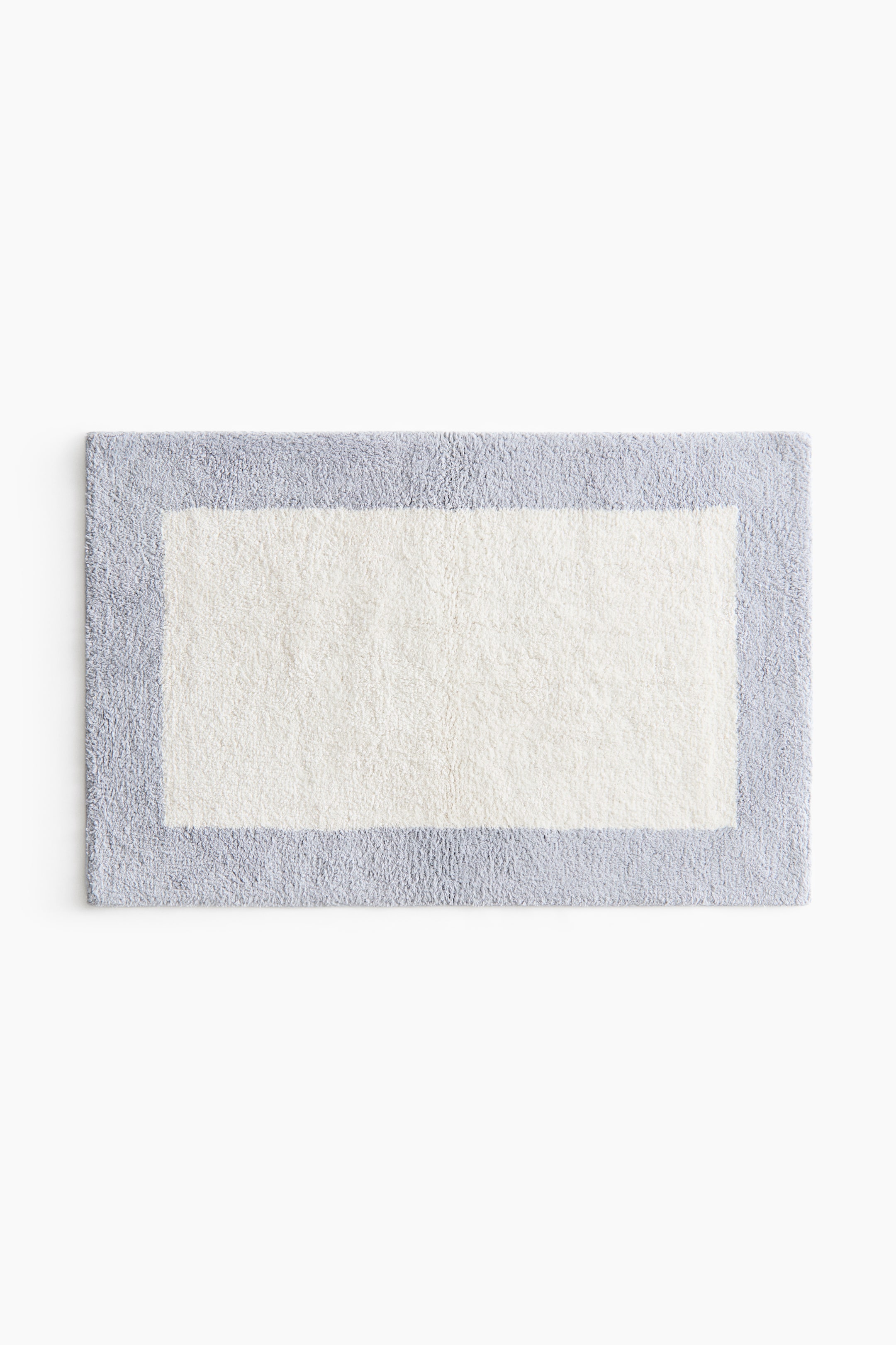 View larger image: The bath mat, rectangular in shape, is positioned front-facing, showcasing its tufted surface. It presents a cream centre, elegantly bordered by a light grey frame.