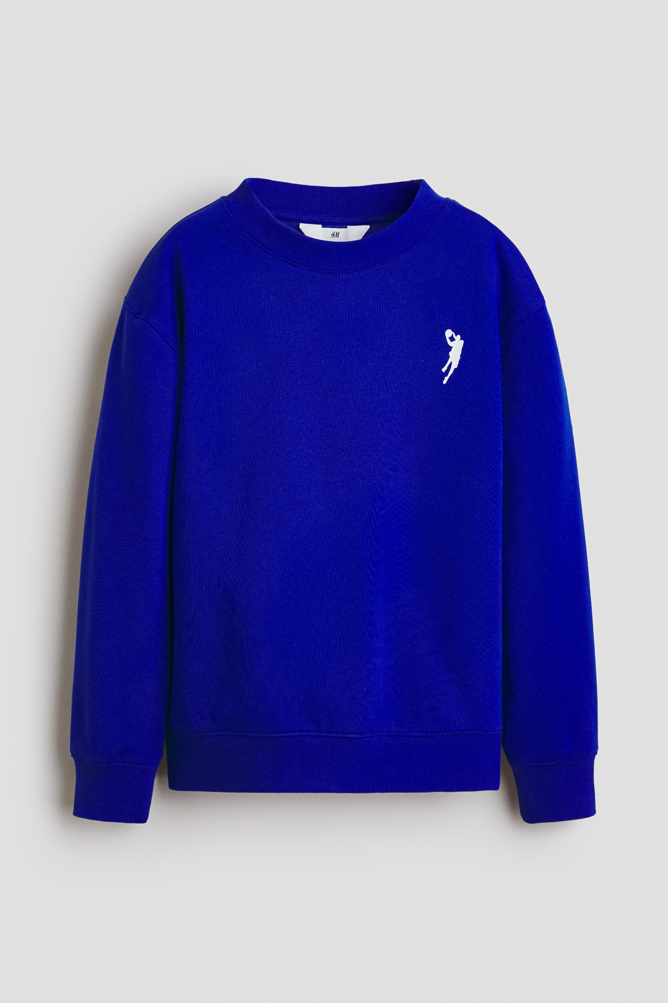 View larger image: The front of the royal blue sweatshirt is showcased, highlighting a ribbed crew neck, long sleeves with ribbed cuffs, and a ribbed hem. A white embroidered graphic of a basketball player is featured on the left chest.
