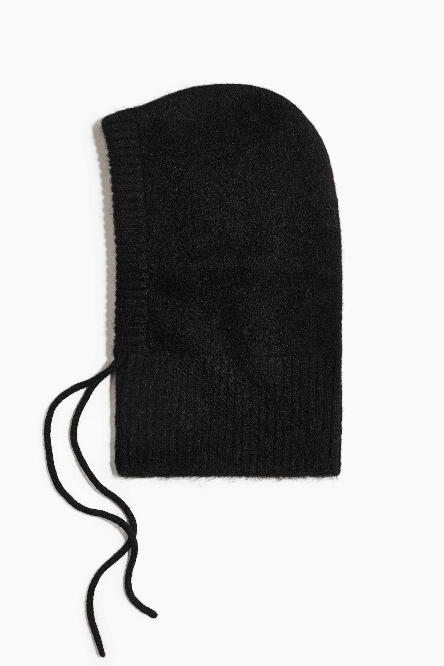 A black knitted hood is laid flat in side profile, showcasing a fuzzy texture with a ribbed border around the face opening and a wide ribbed band at the neck. Two thin knitted ties hang from the lower front corner of the hood.