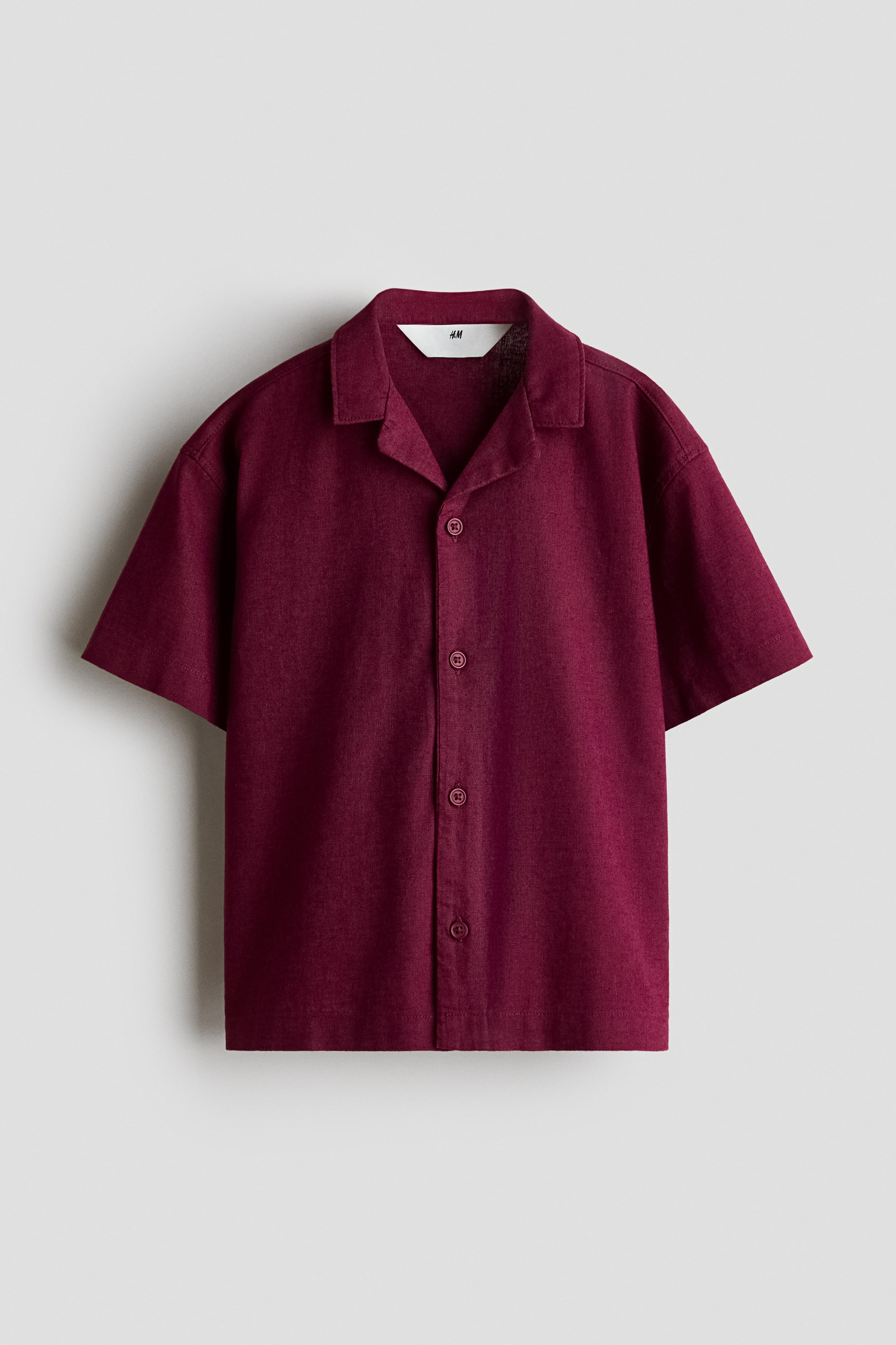 View larger image: A deep red short-sleeved shirt is showcasing its front, boasting a revere collar, five dark buttons along the placket, and a subtle textured fabric finish.