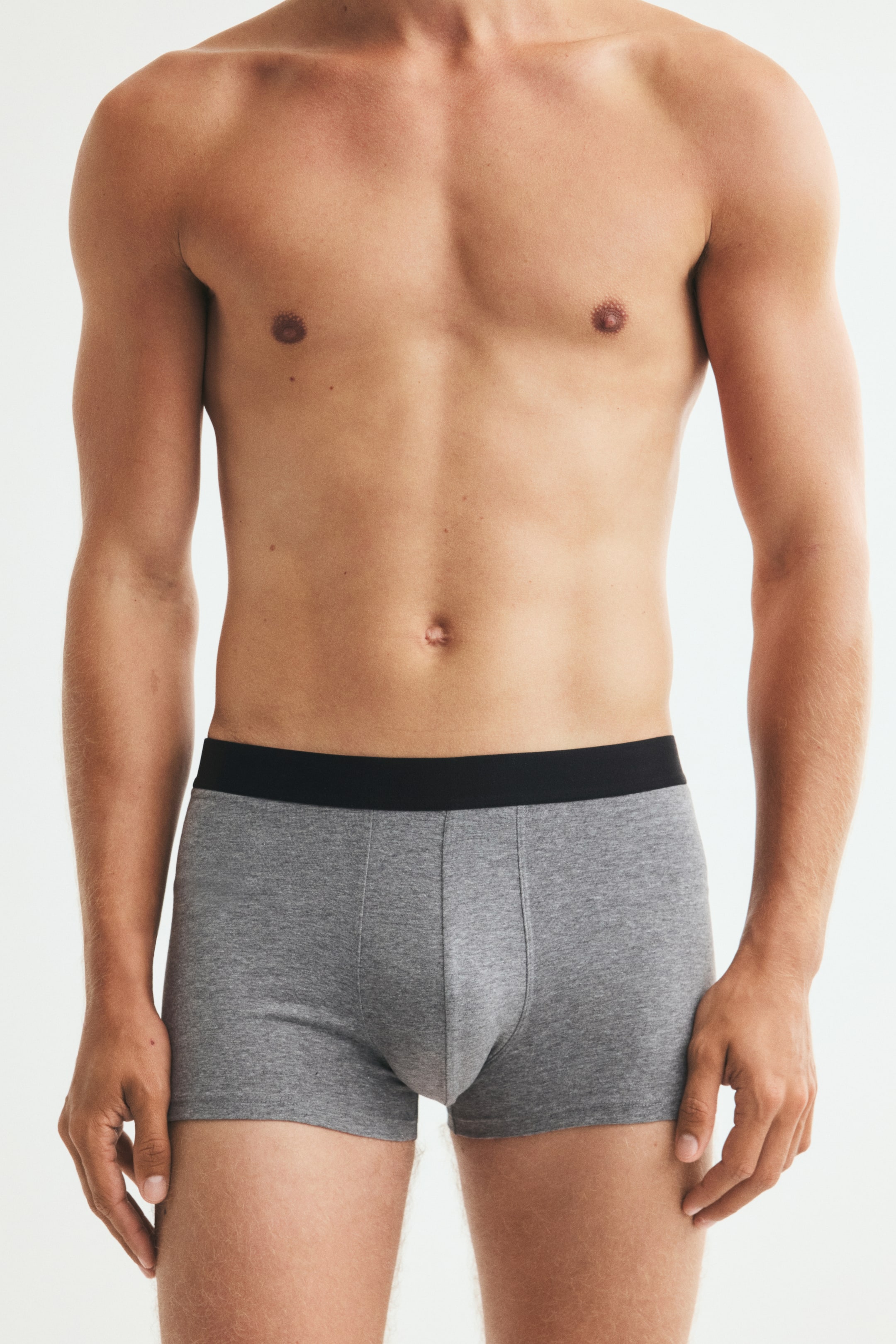 Visualizza immagine più grande: Il modello indossa boxer aderenti grigi con una fascia elastica nera a contrasto. La biancheria intima aderente presenta un tessuto grigio mélange e un pannello frontale sagomato.