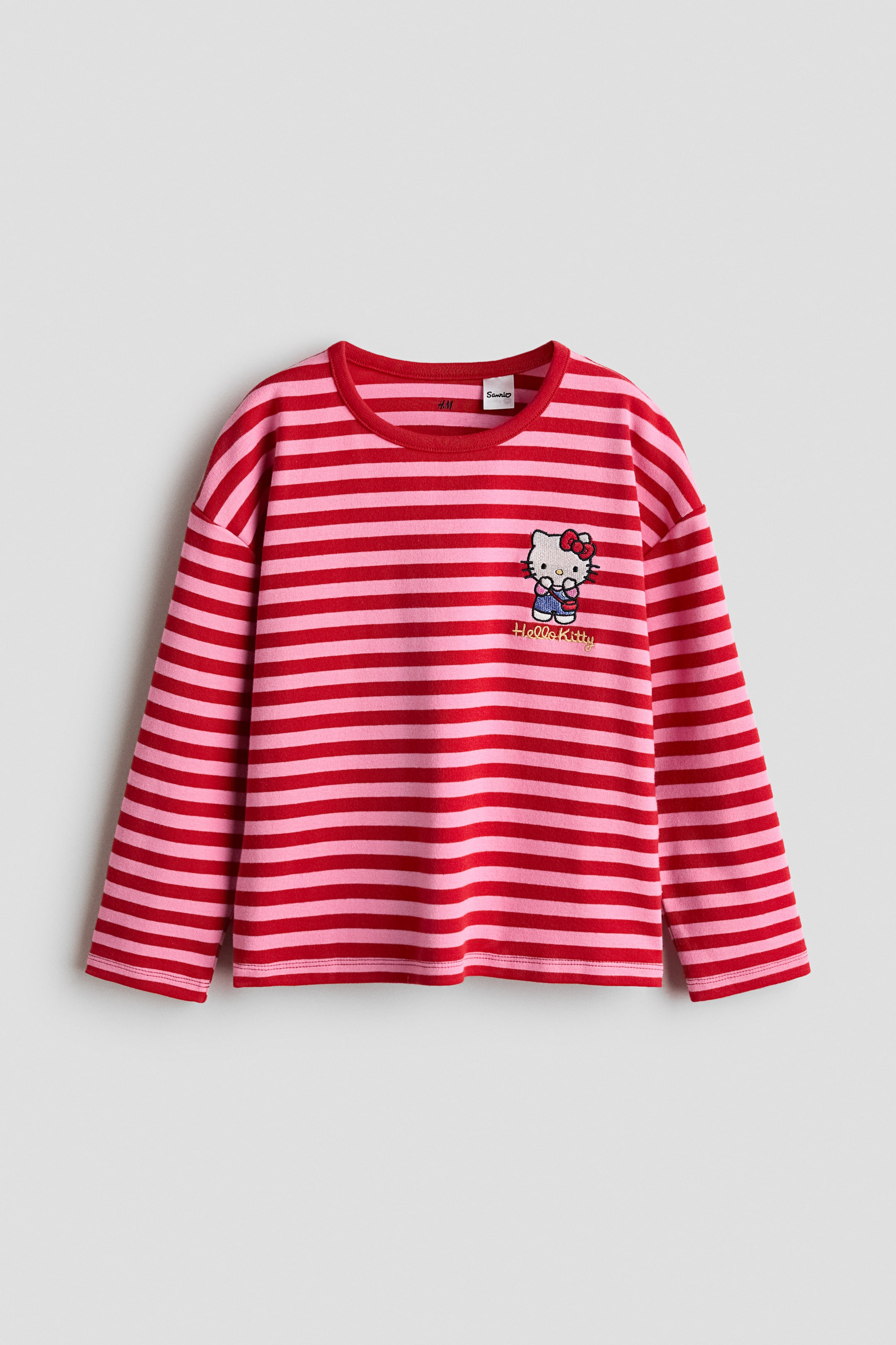 View larger image: A long-sleeved top featuring pink and red horizontal stripes, a round neckline, and an embroidered Hello Kitty character with "Hello Kitty" text underneath on the left chest.