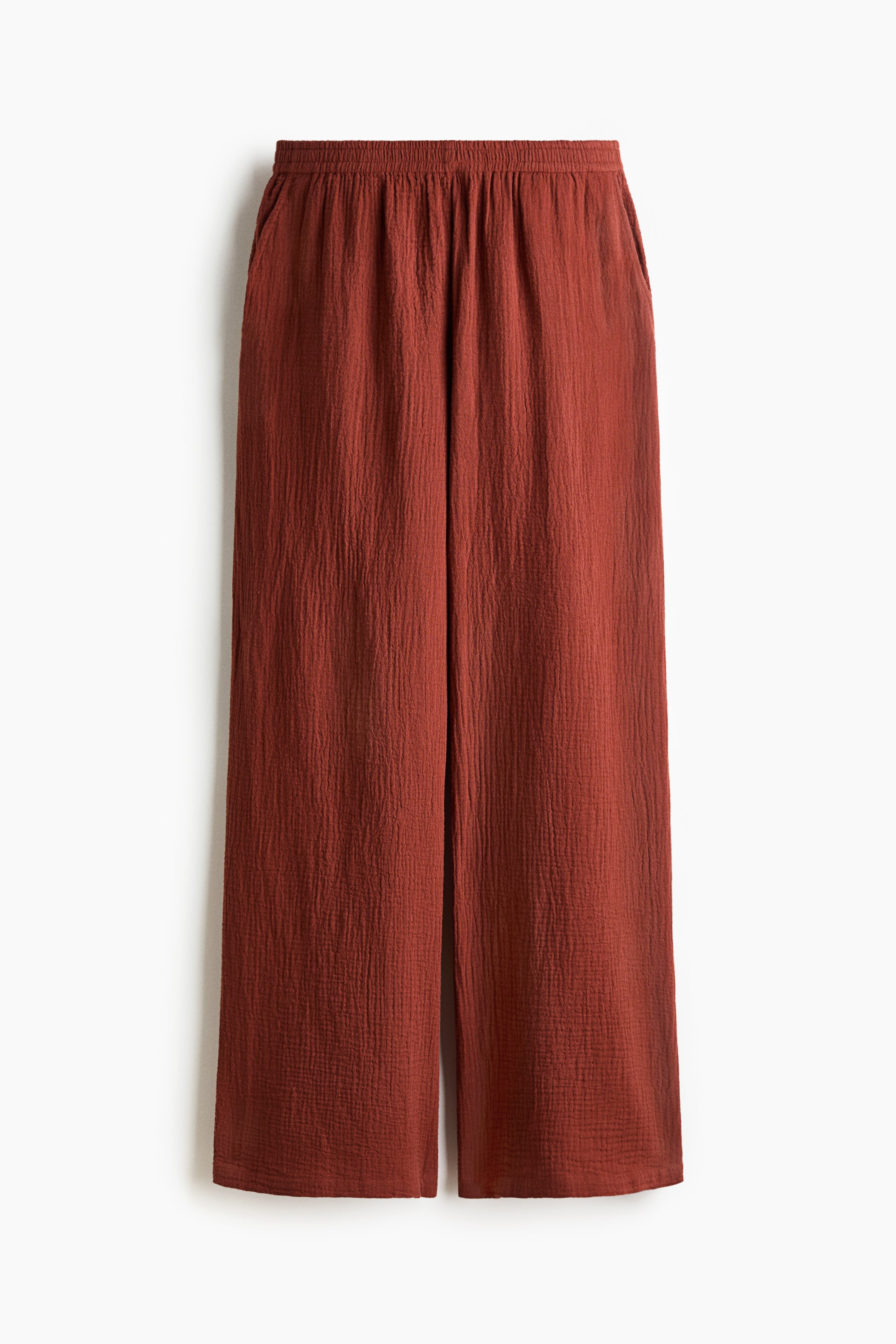 View larger image: Rust-coloured wide-leg pants feature an elasticized waistband and side pockets, displaying a crinkled, textured fabric at the front.