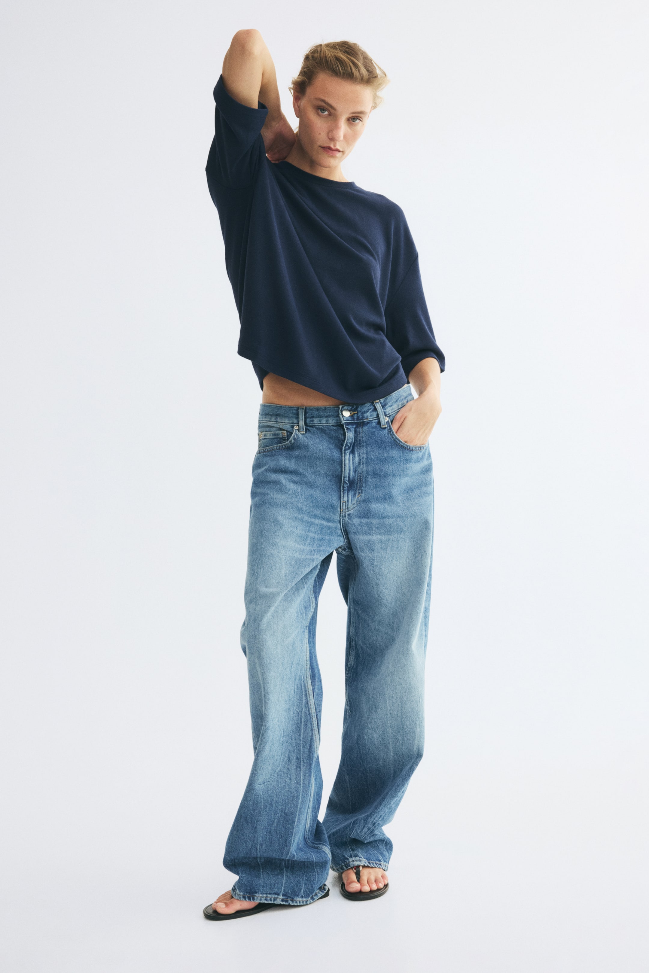 View larger image: A navy blue crewneck T-shirt with relaxed, elbow-length sleeves is paired with wide-leg, light-wash blue jeans in a front-facing view. The relaxed-fit jeans feature a faded wash, a low-to-mid rise waist, and a classic five-pocket design.