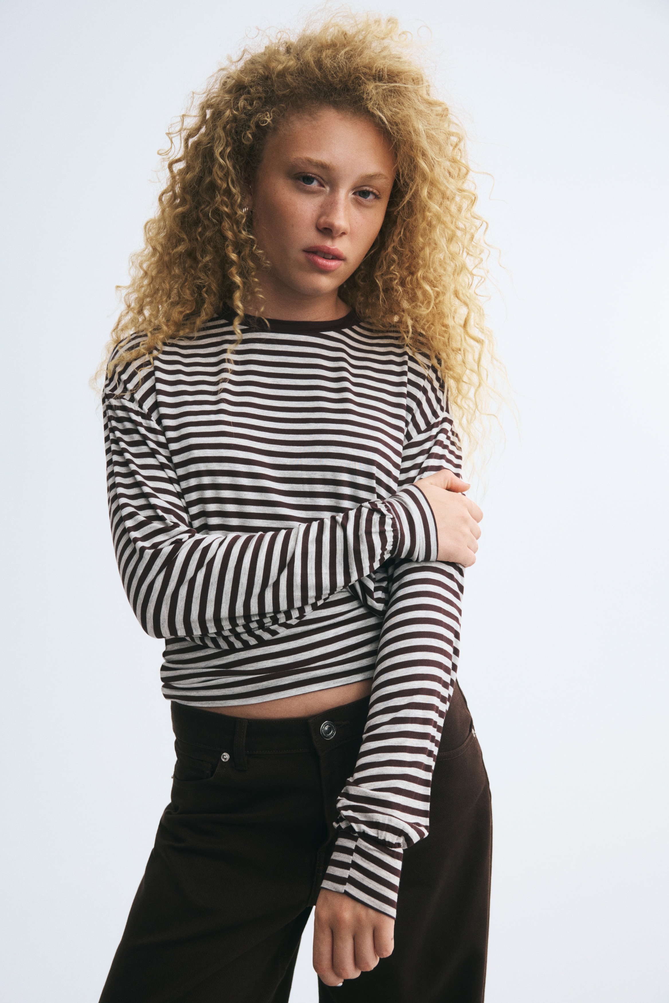 A long-sleeved striped top shown from the front features horizontal navy and white stripes with a solid navy crew neck. It has a gathered waistline that creates a blouson-style bodice and long sleeves ending in fitted, ribbed cuffs.