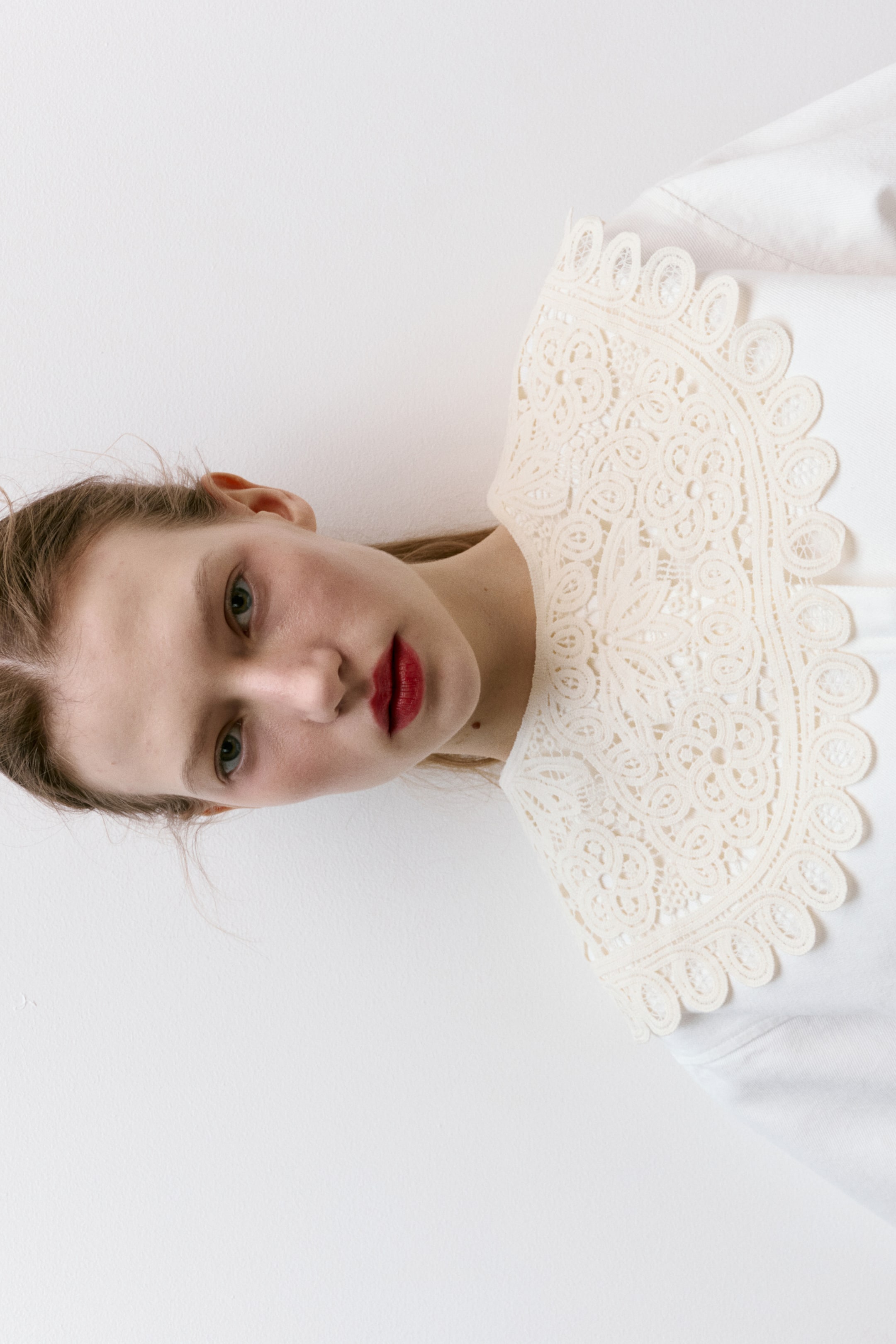 View larger image: A decorative, cream-coloured lace collar embellishes a white garment, showcasing elaborate floral patterns and a scalloped edge, lying flat and spreading wide across the shoulders.
