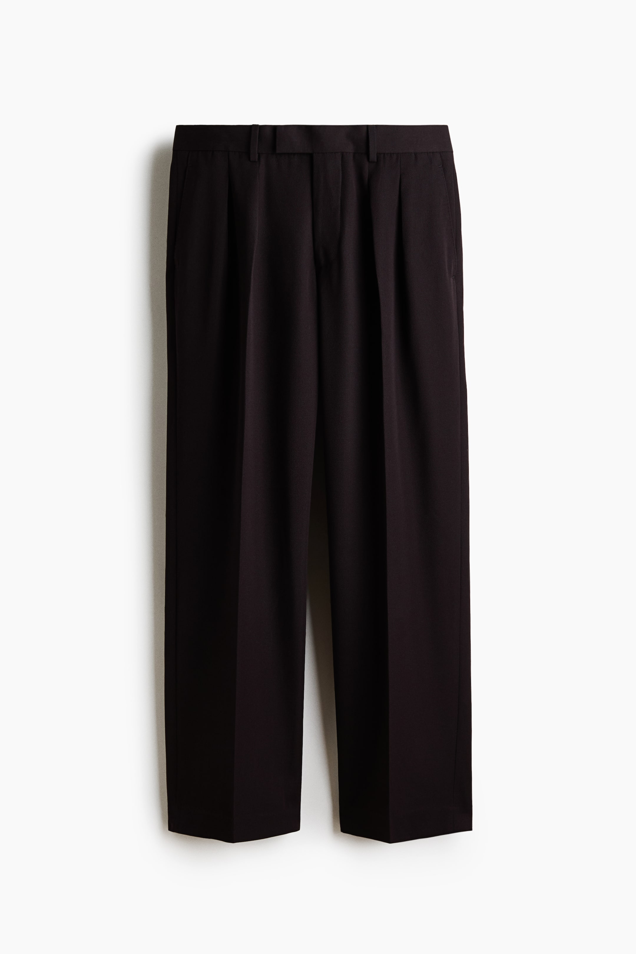 View larger image: Black trousers are hanging, featuring a pleated front with two inward-facing pleats on each side. They are showcasing belt loops, straight side pockets, and a wide, straight leg with an uncuffed hem.