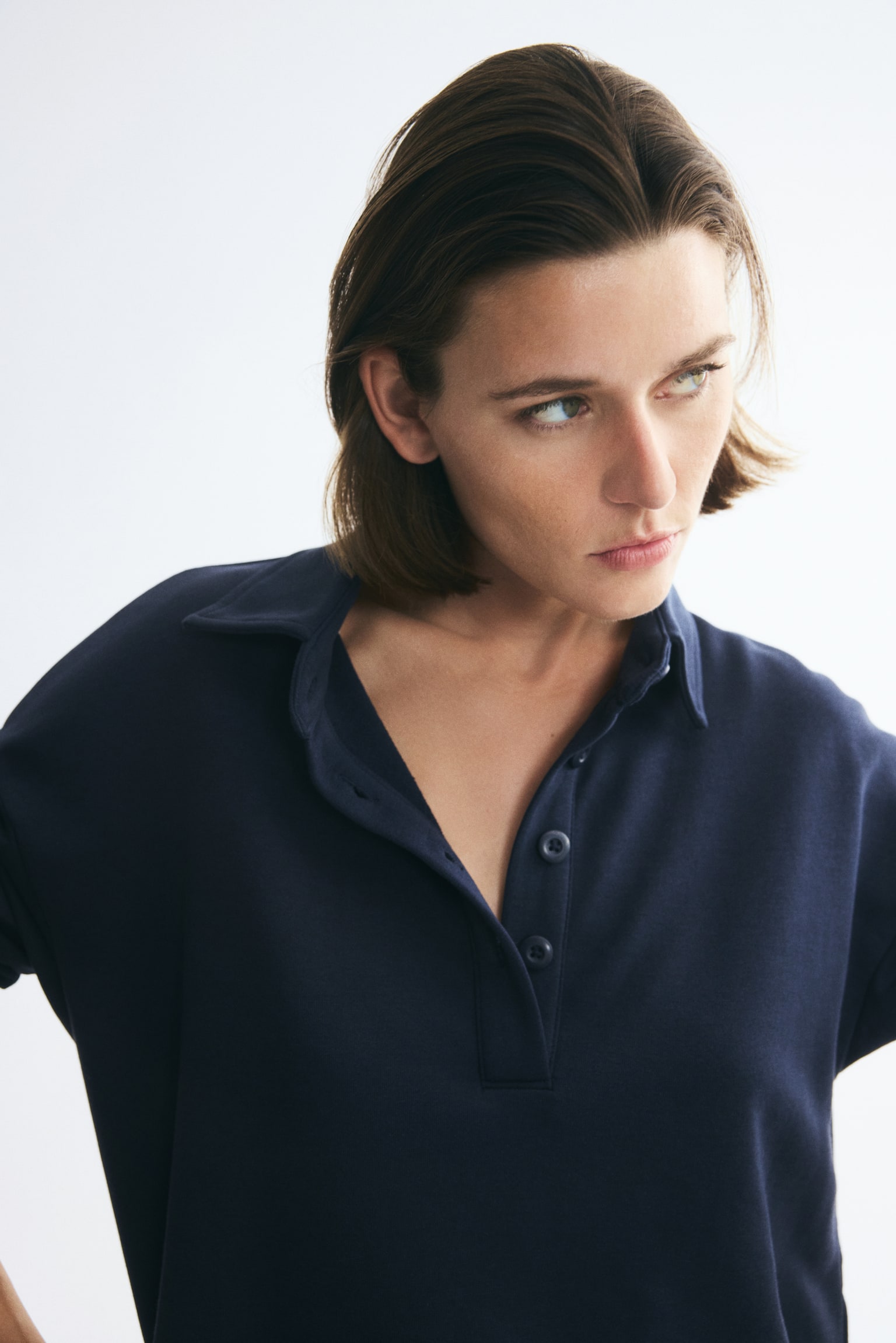A navy long-sleeved top is showcased front-facing. It boasts a spread polo collar and a four-button placket. The top is crafted with dropped shoulders and wide cuffs. - 1