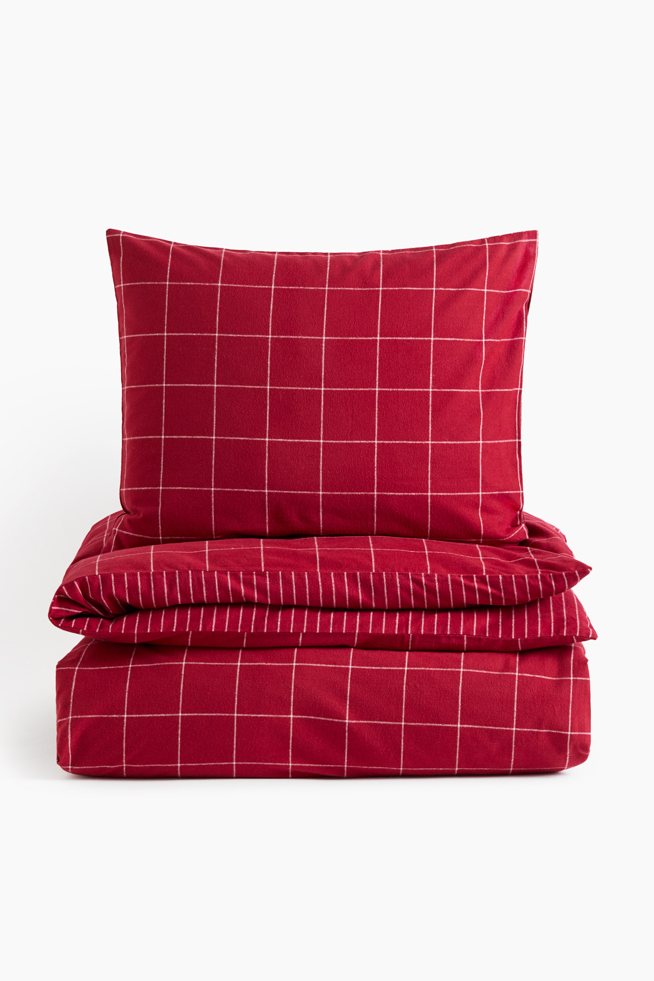 View larger image: A single quilt cover set made of red cotton flannel featuring a white grid pattern is resting in a folded stack, facing front. The set includes a matching rectangular pillowcase sitting on top of the neatly folded quilt cover.