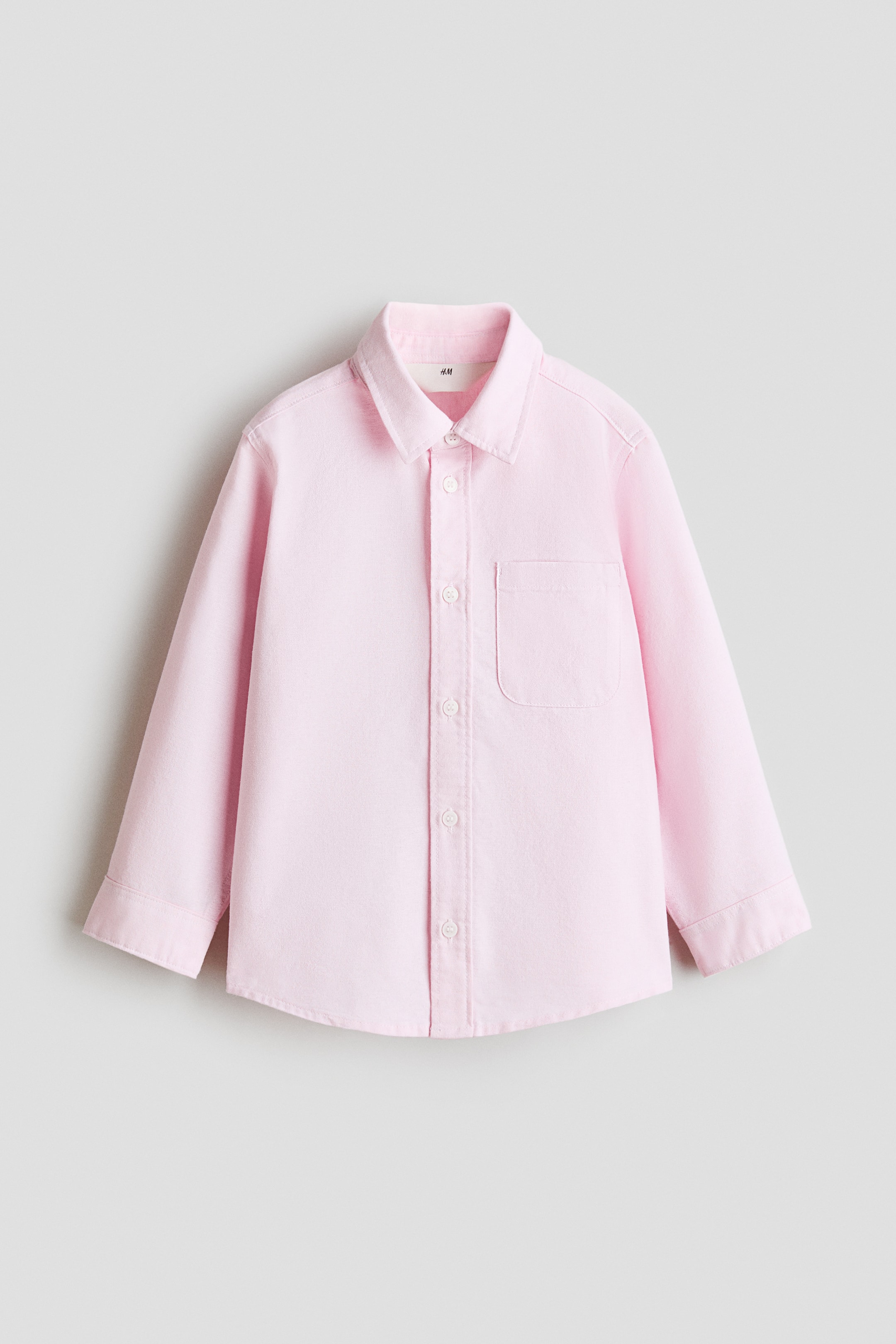 View larger image: A pink shirt in a cotton weave is shown in its FRONT view, showcasing a turn-down collar, buttons along the front, a patch chest pocket, long sleeves with buttoned cuffs, and a rounded hem.