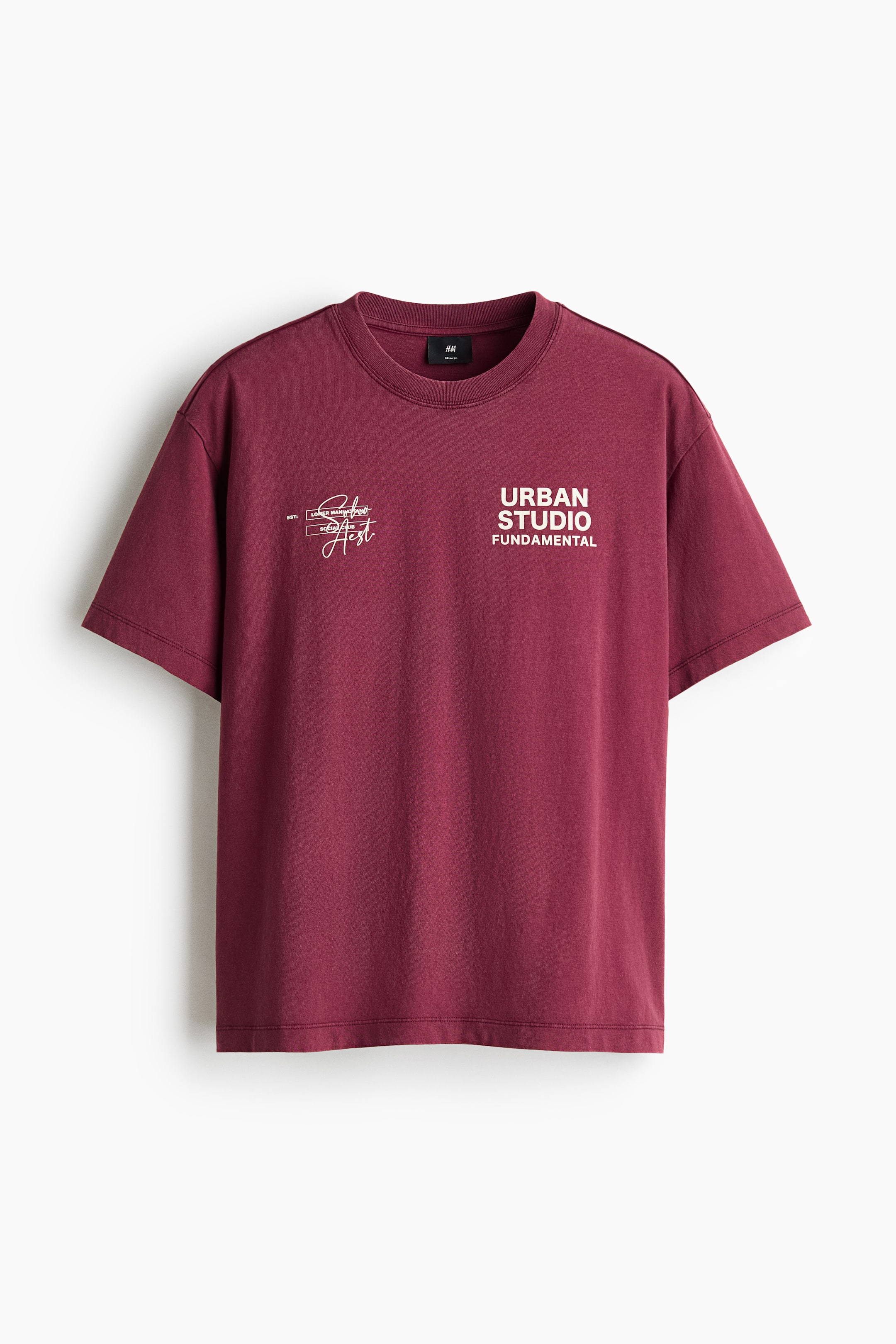 View larger image: Presenting the FRONT of a maroon cotton jersey t-shirt, this piece showcases a relaxed fit with dropped shoulders and a straight-cut hem. It is crafted with a round, rib-trimmed neckline and features white graphic prints, including "urban studio fundamental," prominently on the chest.