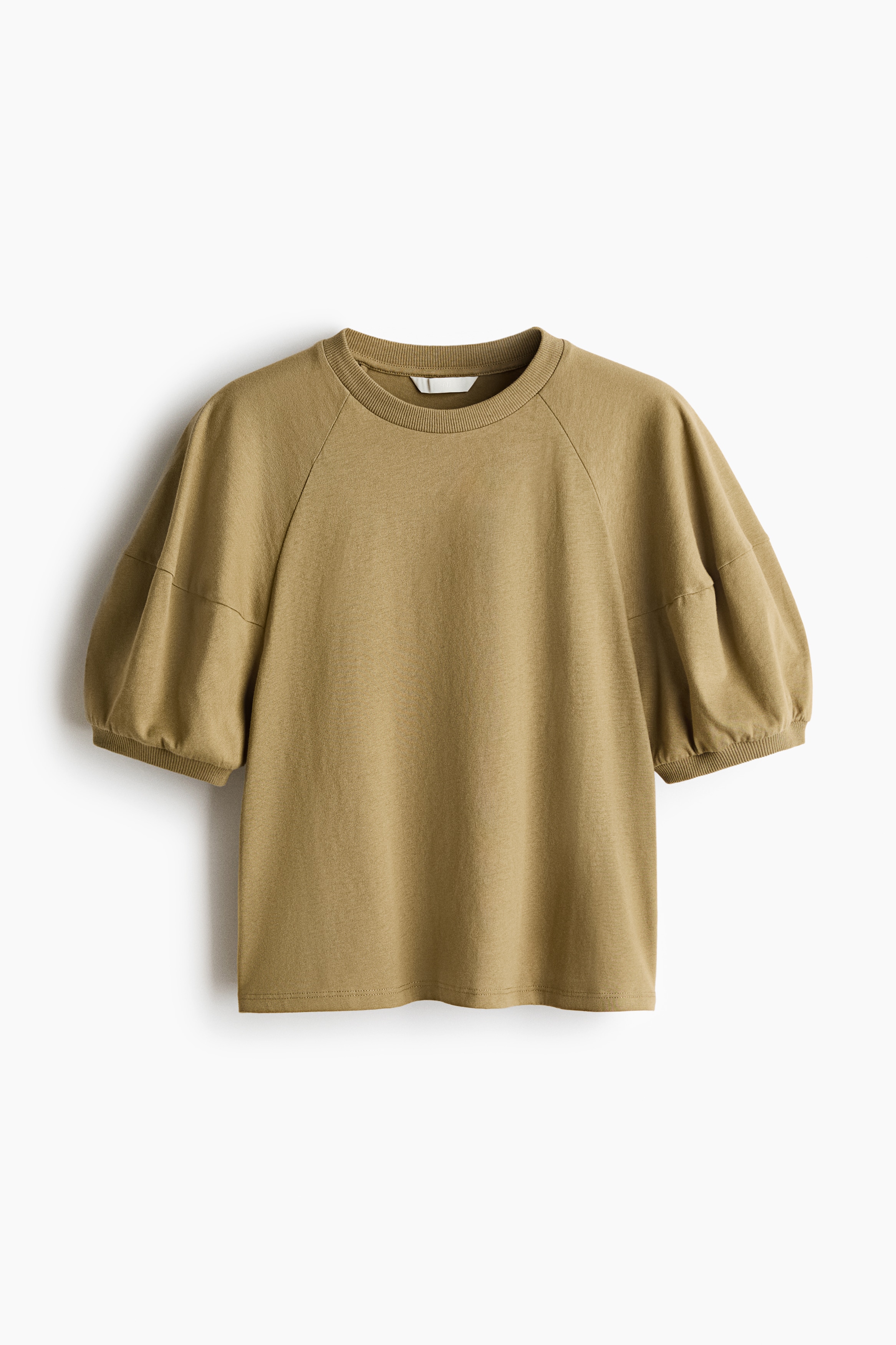 An olive-green cotton jersey top featuring a round, rib-trimmed neckline and short, puffed raglan sleeves with ribbed cuffs is being worn by the model. The top is styled with light beige jeans.