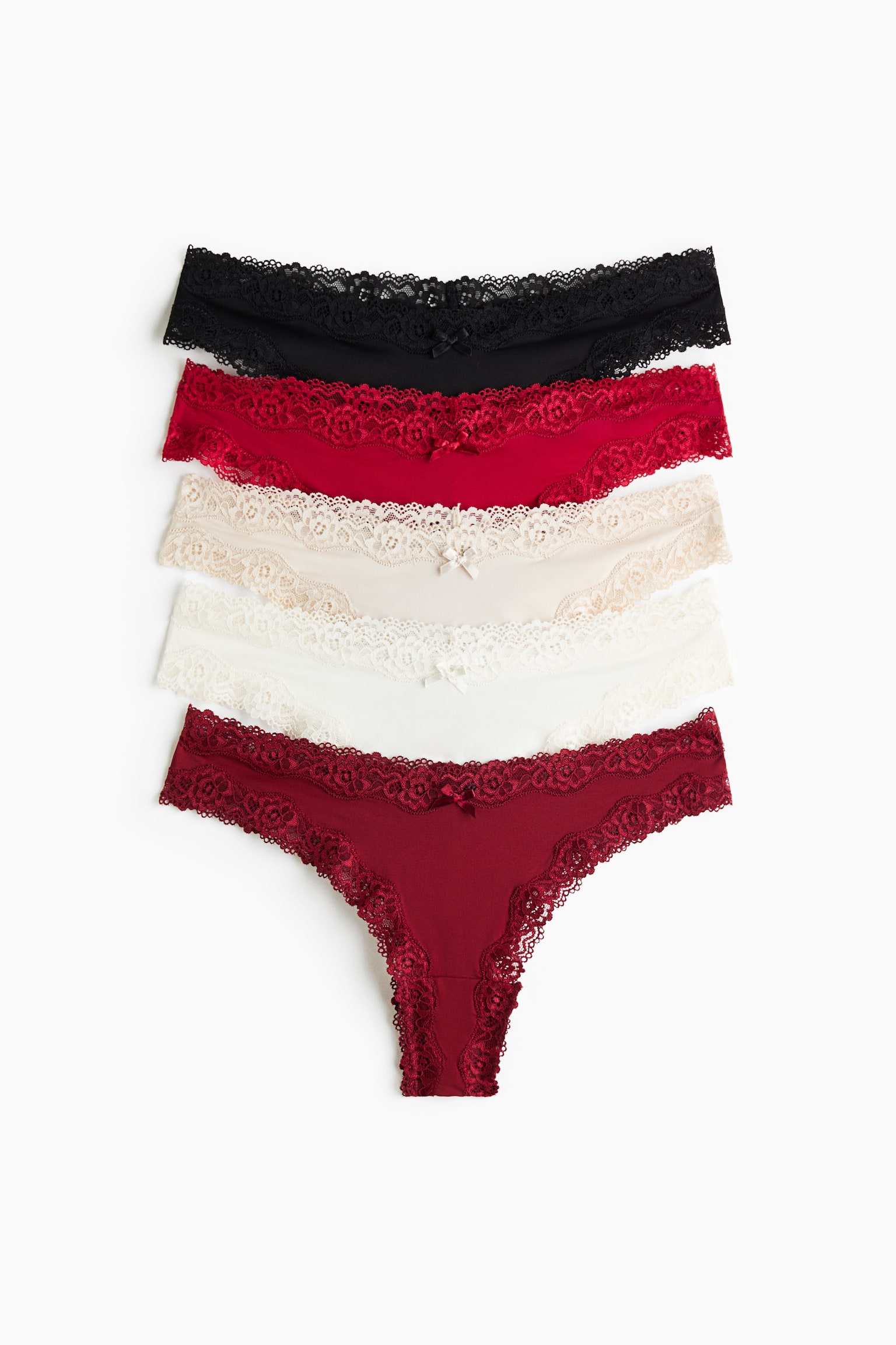 Un set da cinque slip in microfibra e pizzo è mostrato frontalmente, impilato verticalmente nei colori nero, rosso acceso, beige, bianco e rosso scuro. Ogni paio presenta una fascia in vita a V con ampio bordo in pizzo, un piccolo fiocco decorativo al centro sul davanti e sgambature ad alto taglio.