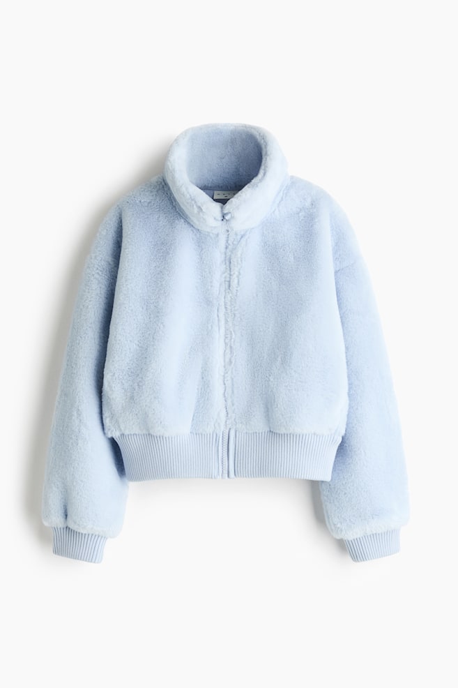 Se muestra una chamarra de peluche sintÃ©tico en color azul claro, vista de frente, con textura suave, cuello alto tipo chimenea y cierre completo al frente con cierre. La chamarra estÃ¡ diseÃ±ada con hombros caÃ­dos, mangas voluminosas y puÃ±os y dobladillo a juego en tejido de punto acanalado. - 1