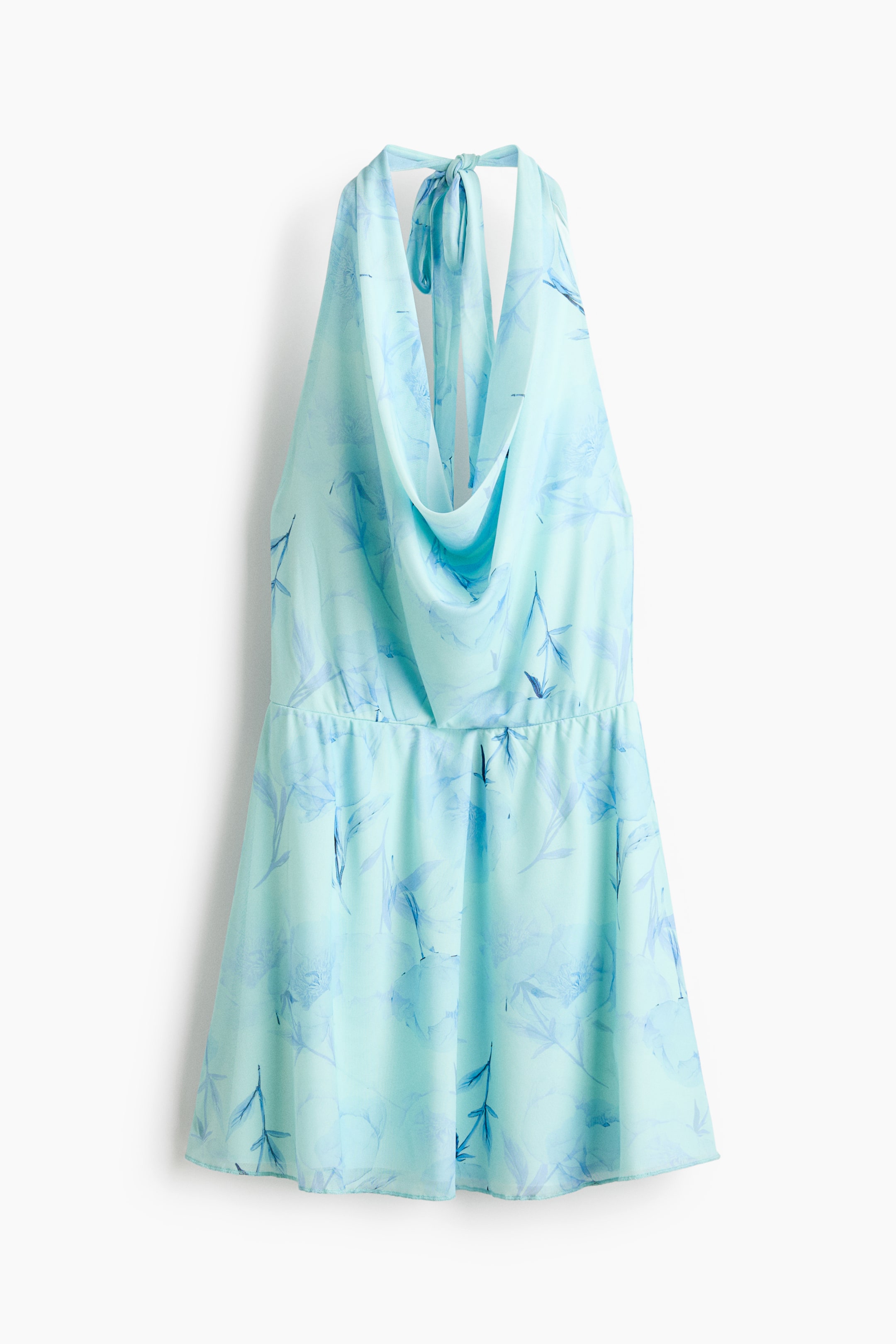 View larger image: A light blue romper is displayed from the front, showcasing a halter neckline with a tied back, a draped cowl neck, and an elasticized waist. The fabric exhibits a subtle floral or leaf pattern in darker blue shades.