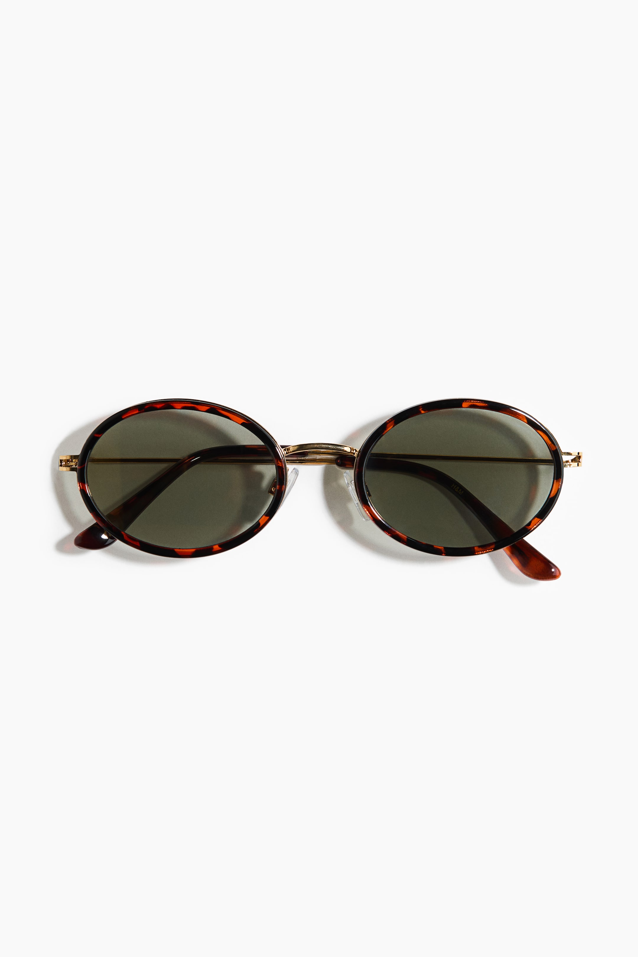 View larger image: Oval sunglasses are featuring dark tinted lenses set in tortoiseshell frames. 