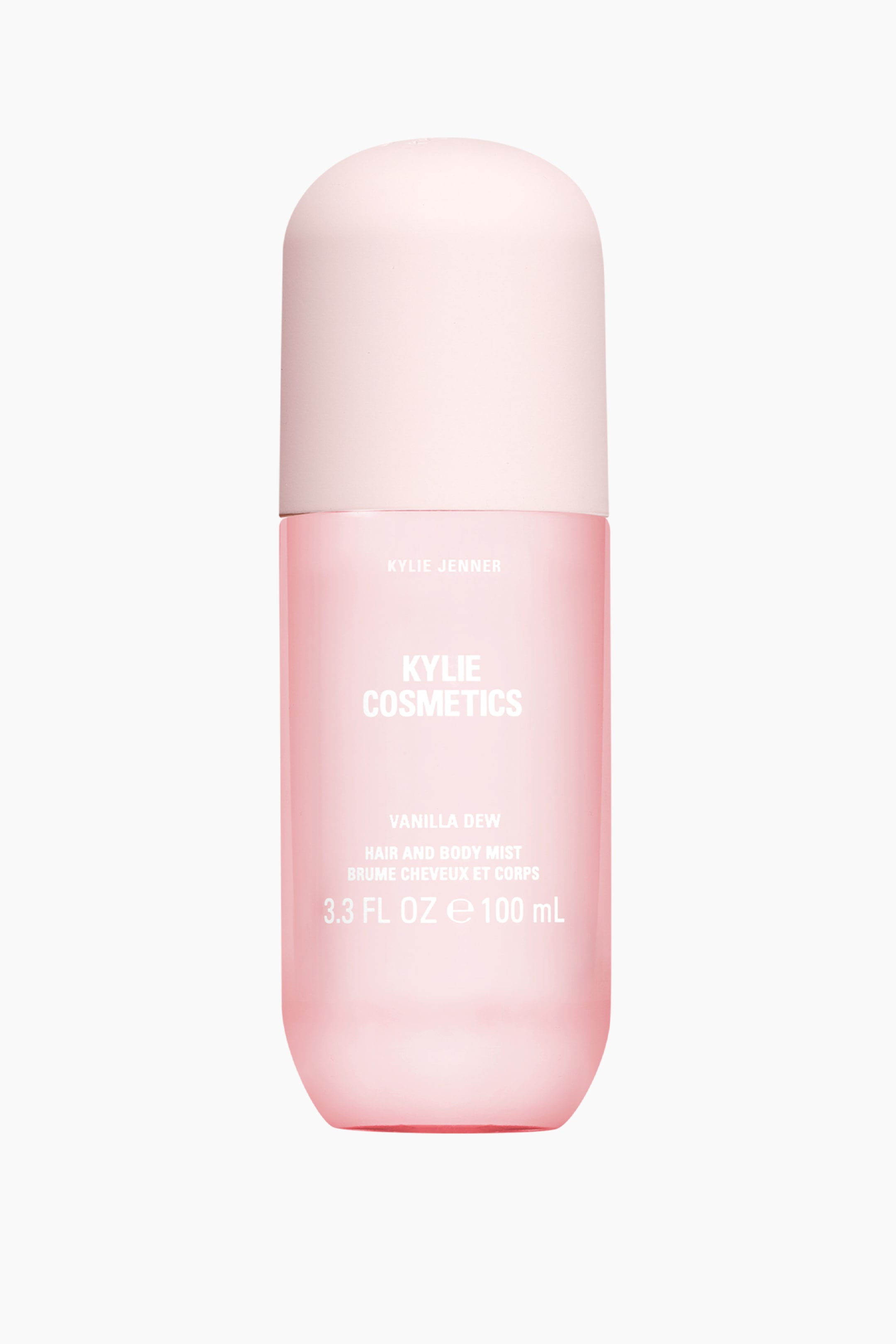 Se større billede: En cylindrisk Kylie Cosmetics Vanilla Dew Hair and Body Mist-flaske står oprejst og vender fremad med en gennemsigtig rosa krop, en lyserosa afrundet hætte og hvid tekst, der angiver produktnavn, mærke og volumen.