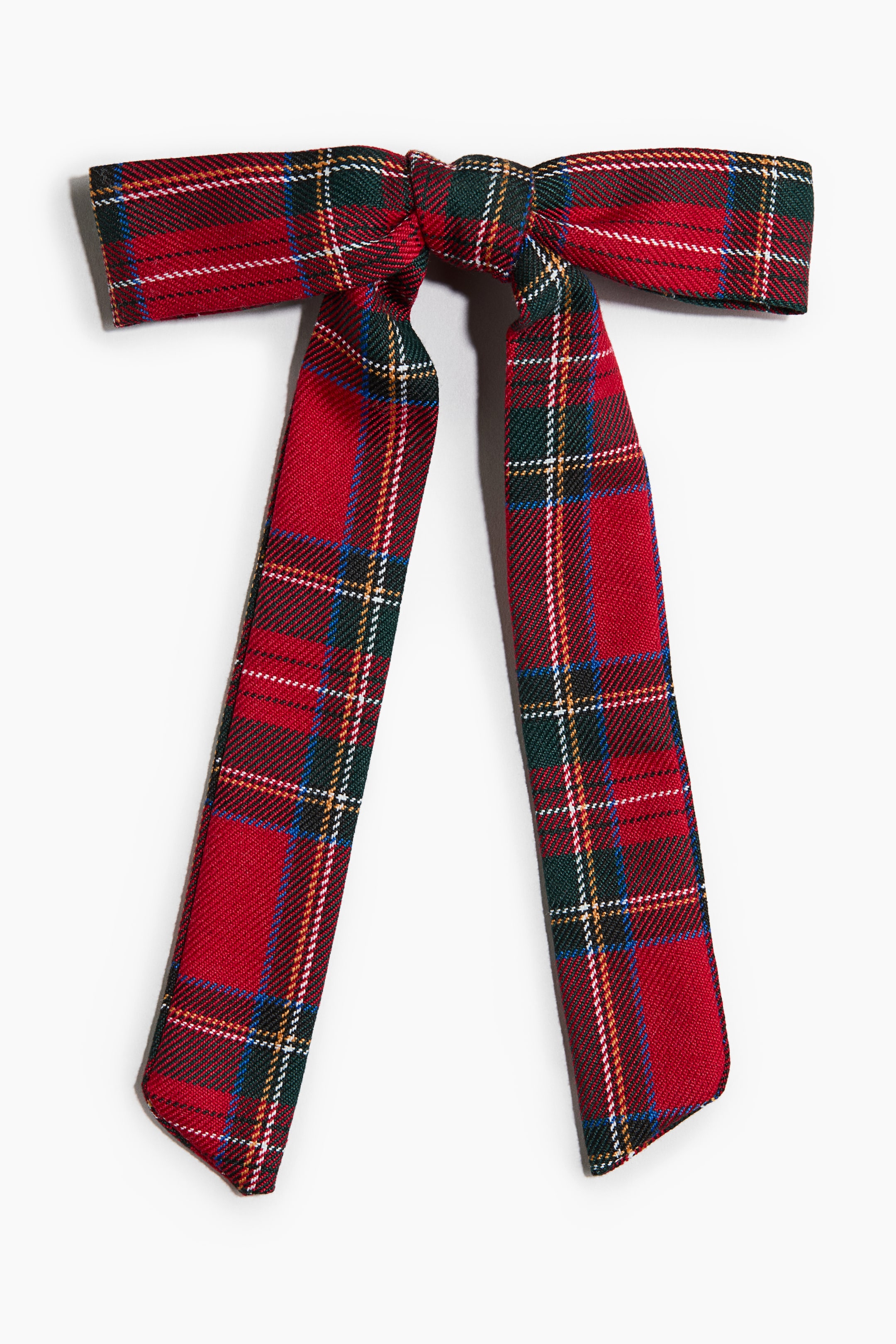 Se større billede: En rød tartan-sløjfe ses forfra med et klassisk mønster af røde, grønne, hvide og gule striber. Sløjfen har en struktureret midterknude med to lange, brede stofhaler, der hænger nedad.