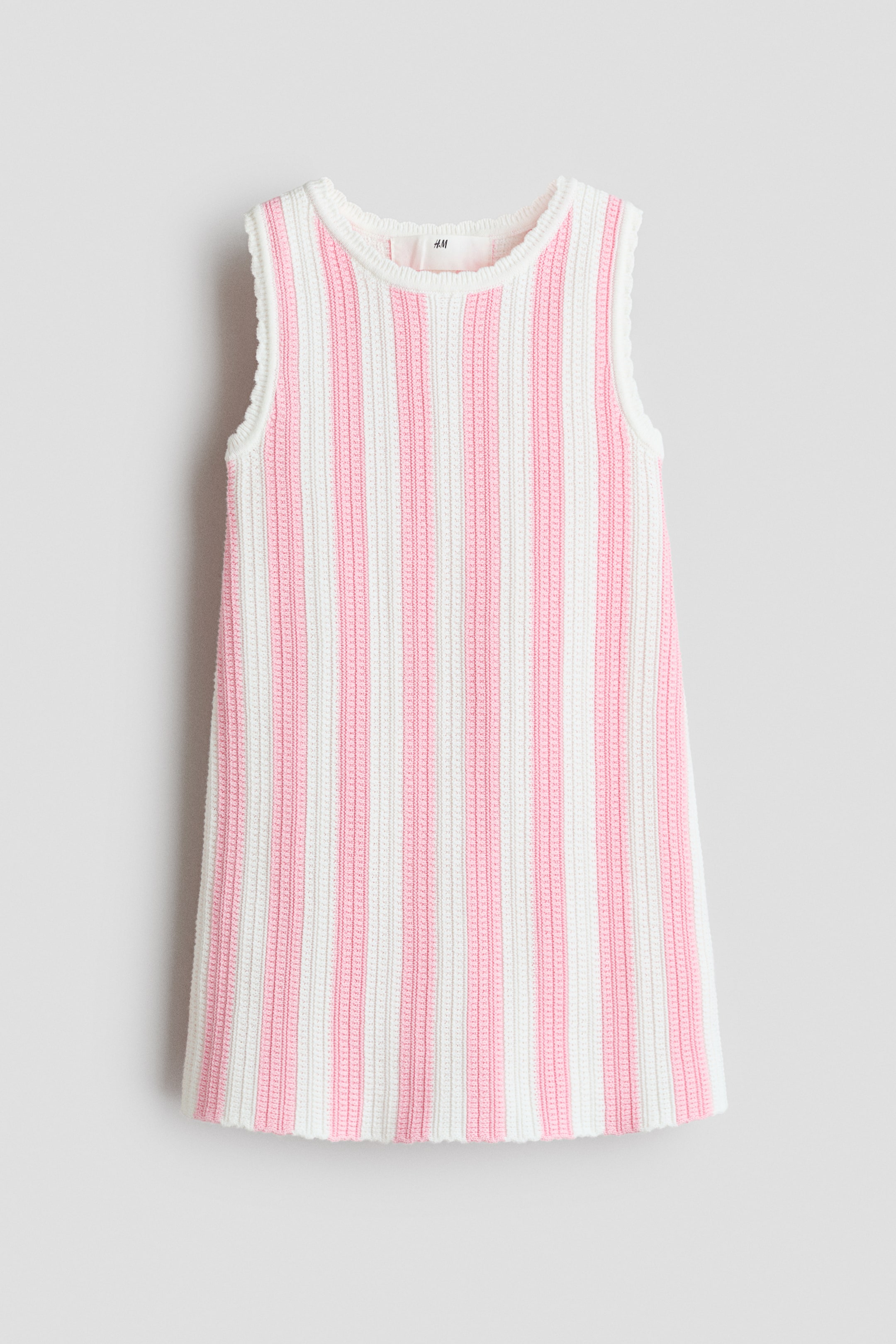 Größeres Bild ansehen: Ein ärmelloses A-Linien-Kleid zeigt ein weiches, strukturiertes Strickmuster mit abwechselnden vertikalen Streifen in Weiß und Rosa. Es präsentiert eine A-Linien-Silhouette von vorne und verfügt über gerippte Abschlüsse am Ausschnitt und an den Armlöchern.