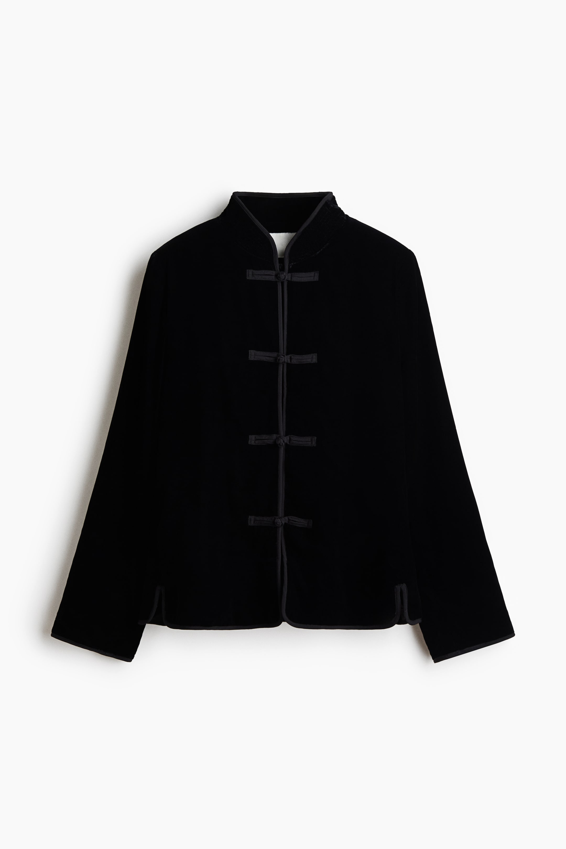 View larger image: A black velvet jacket is shown from the front, featuring a stand-up collar, long sleeves, and four traditional frog closures down the center. The garment features tonal piping along all edges and small side slits at the hem.