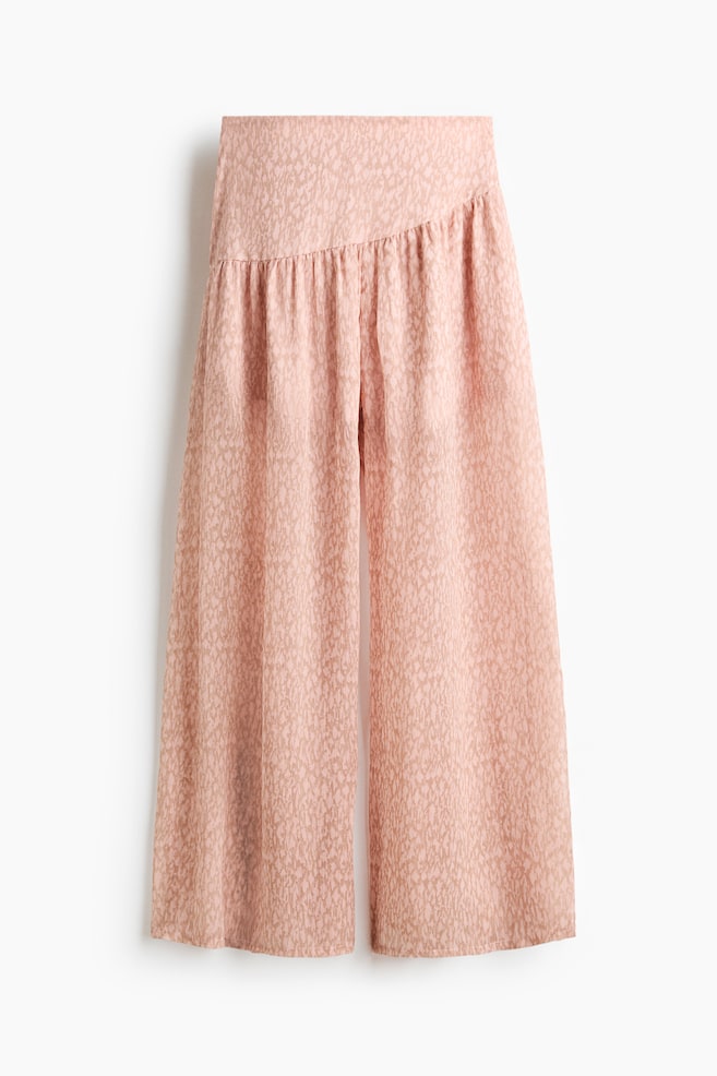 The light pink wide-leg trousers showcase a subtle, all-over abstract design. They boast a wide, flat front waistband with gathers forming beneath it, crafting a flowing, cropped silhouette. - 1