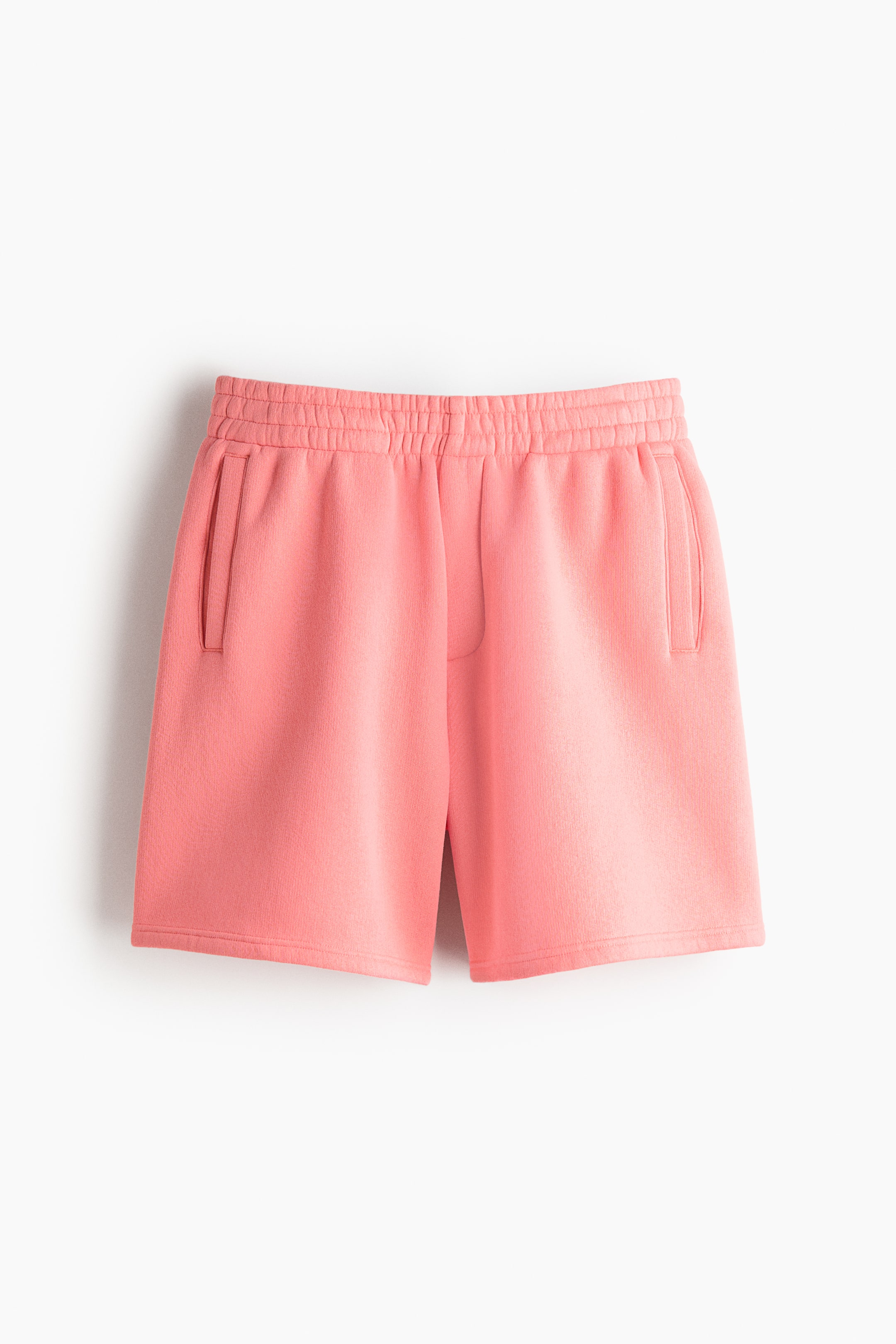 View larger image: "The pink shorts are showcased from a frontal view, highlighting an elastic waistband and two side pockets. Crafted from a textured knit fabric, they offer both style and comfort."
