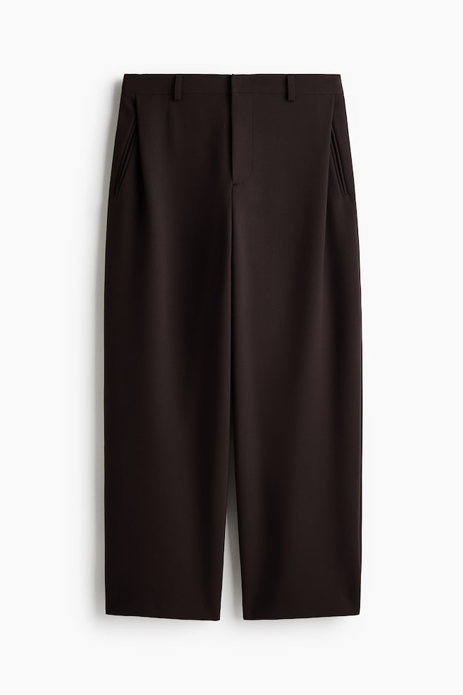 A pair of dark brown trousers is shown from the front, featuring a waistband with belt loops and a concealed front fastening. The design includes angled side pockets and subtle front pleats that flow into structured wide legs. - 1