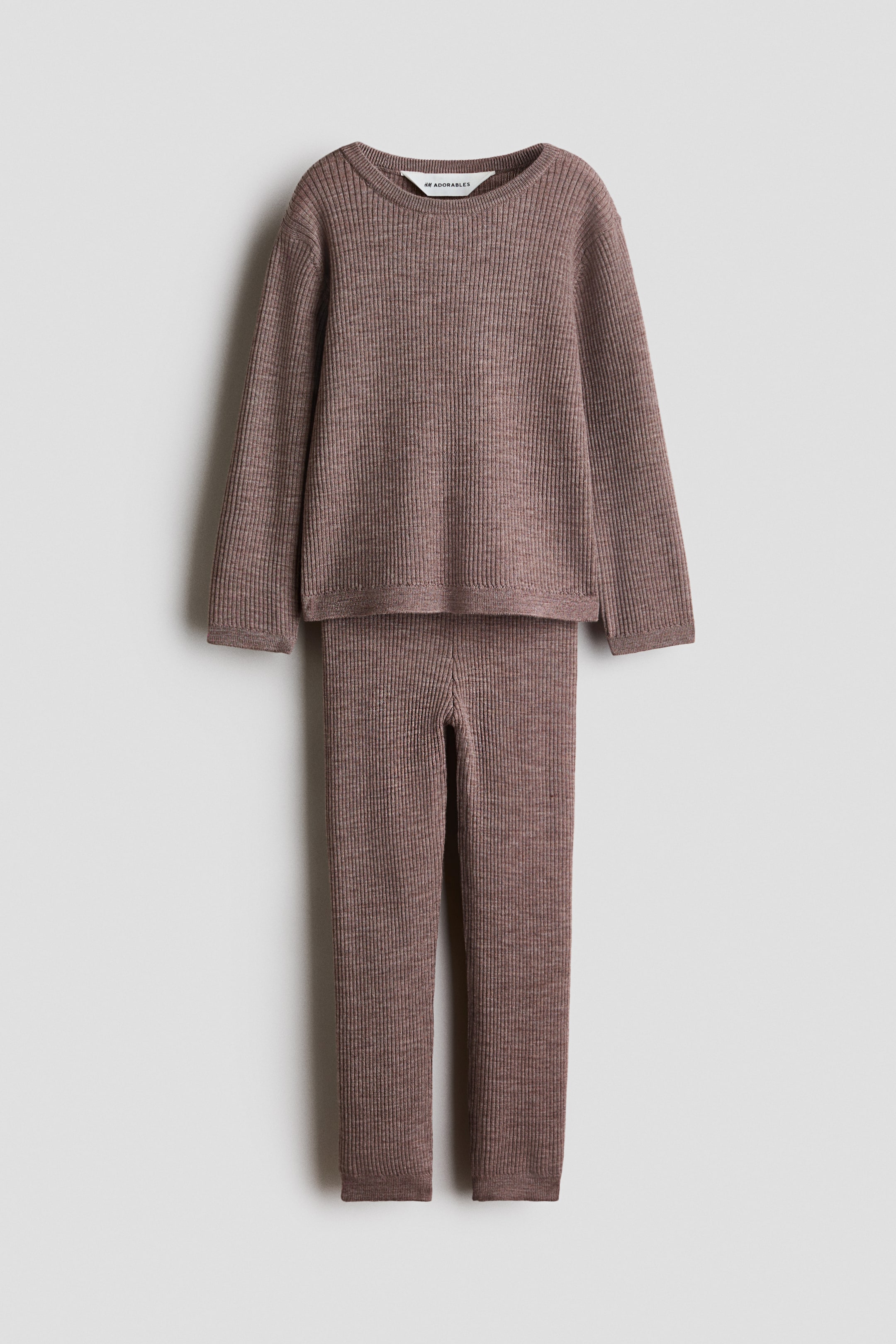 View larger image: Presenting a muted purplish-brown ribbed knit loungewear set, facing forward. The long-sleeved top features a crew neck with a visible brand tag, and the matching long pants showcase the same ribbed texture.