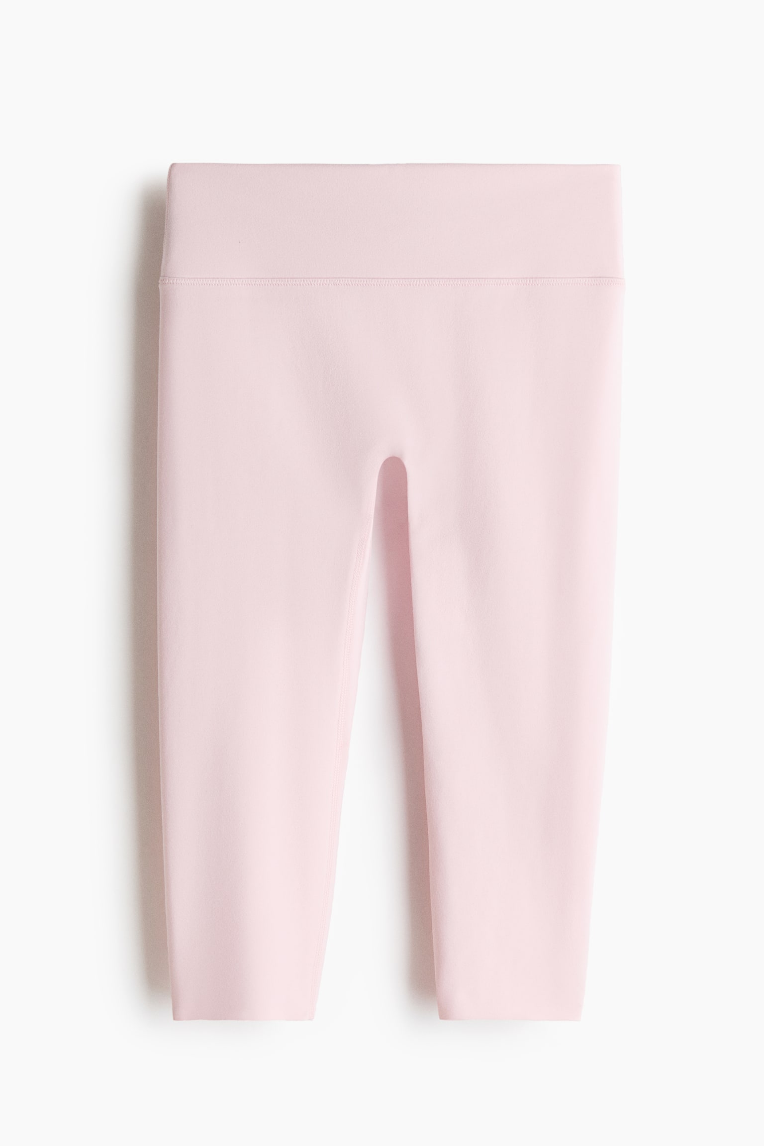 Capri sports leggings with SoftMove are showcased in a soft pink hue, front-facing. They boast a wide, high-rise waistband with a distinct horizontal seam marking its lower boundary, and smooth fabric that extends to a capri length. - 1