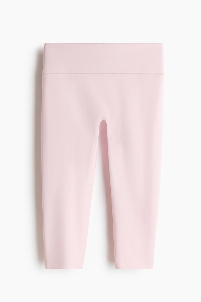 Capri sports leggings with SoftMove are presenting in a pale pink color, facing front. They are featuring a wide, high-rise waistband with a visible horizontal seam defining its lower edge, and smooth fabric extending to a capri length. - 1