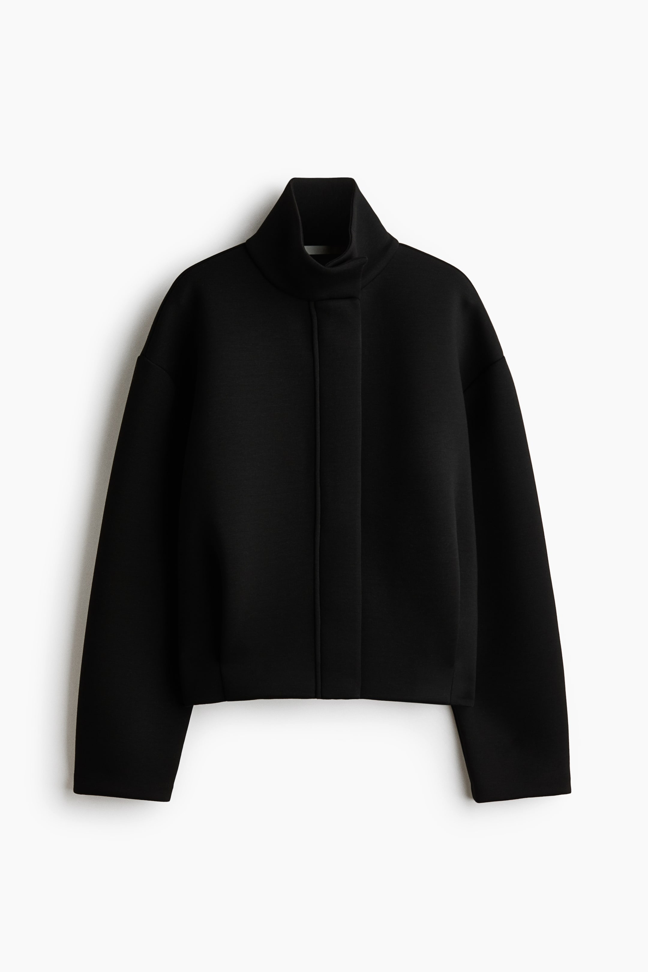 View larger image: A black structured jacket is shown from the front, featuring a high funnel neck and a concealed front placket. It has a boxy, slightly cropped silhouette with dropped shoulders and wide, long sleeves.