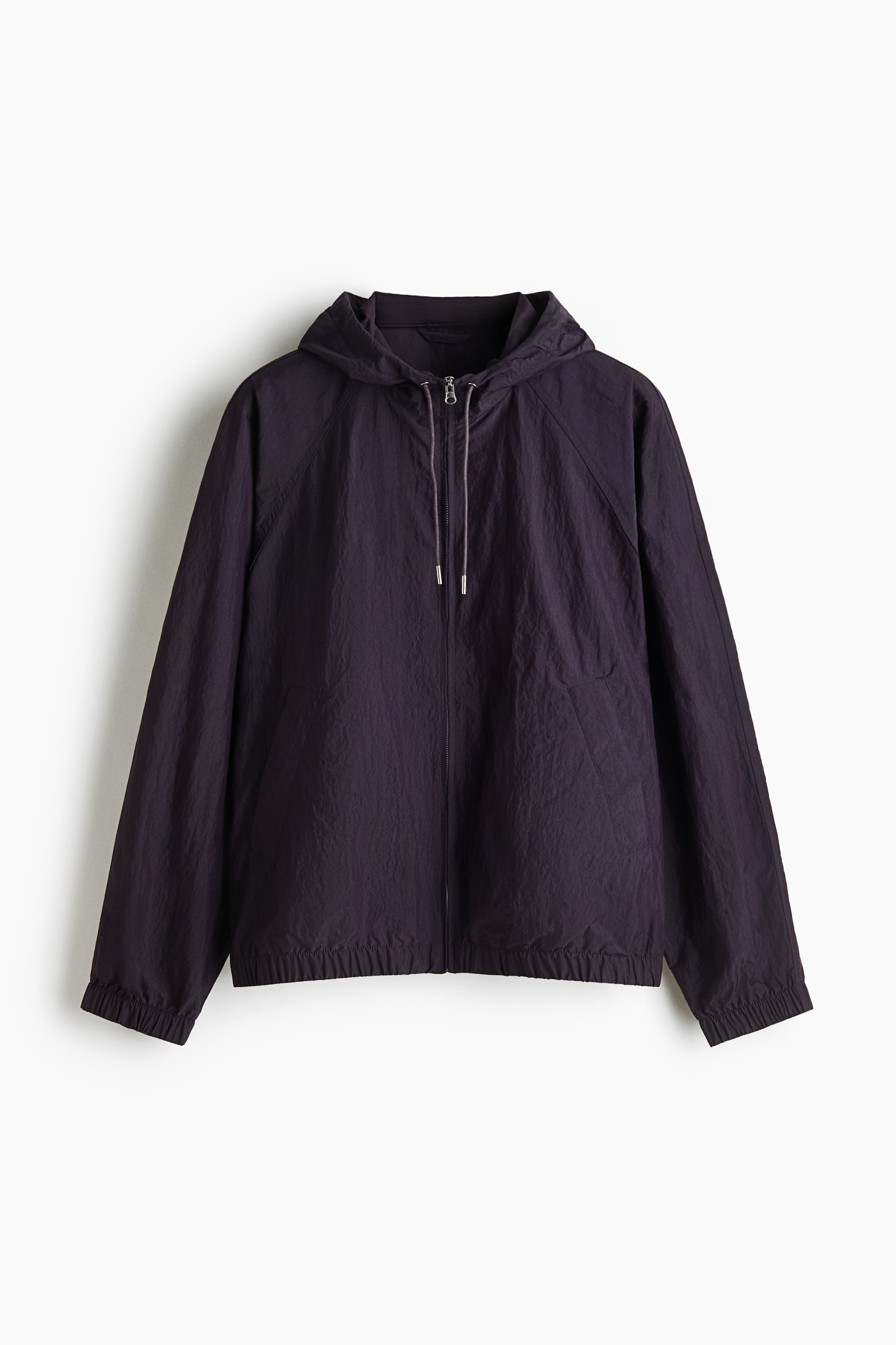 View larger image: A lightweight, deep purple hooded jacket is shown from the front, featuring a crinkled texture, a full-length front zipper, and an adjustable drawstring hood with metal-tipped cords. The jacket features long raglan sleeves with elasticated cuffs, an elasticated hem, and discreet side pockets.