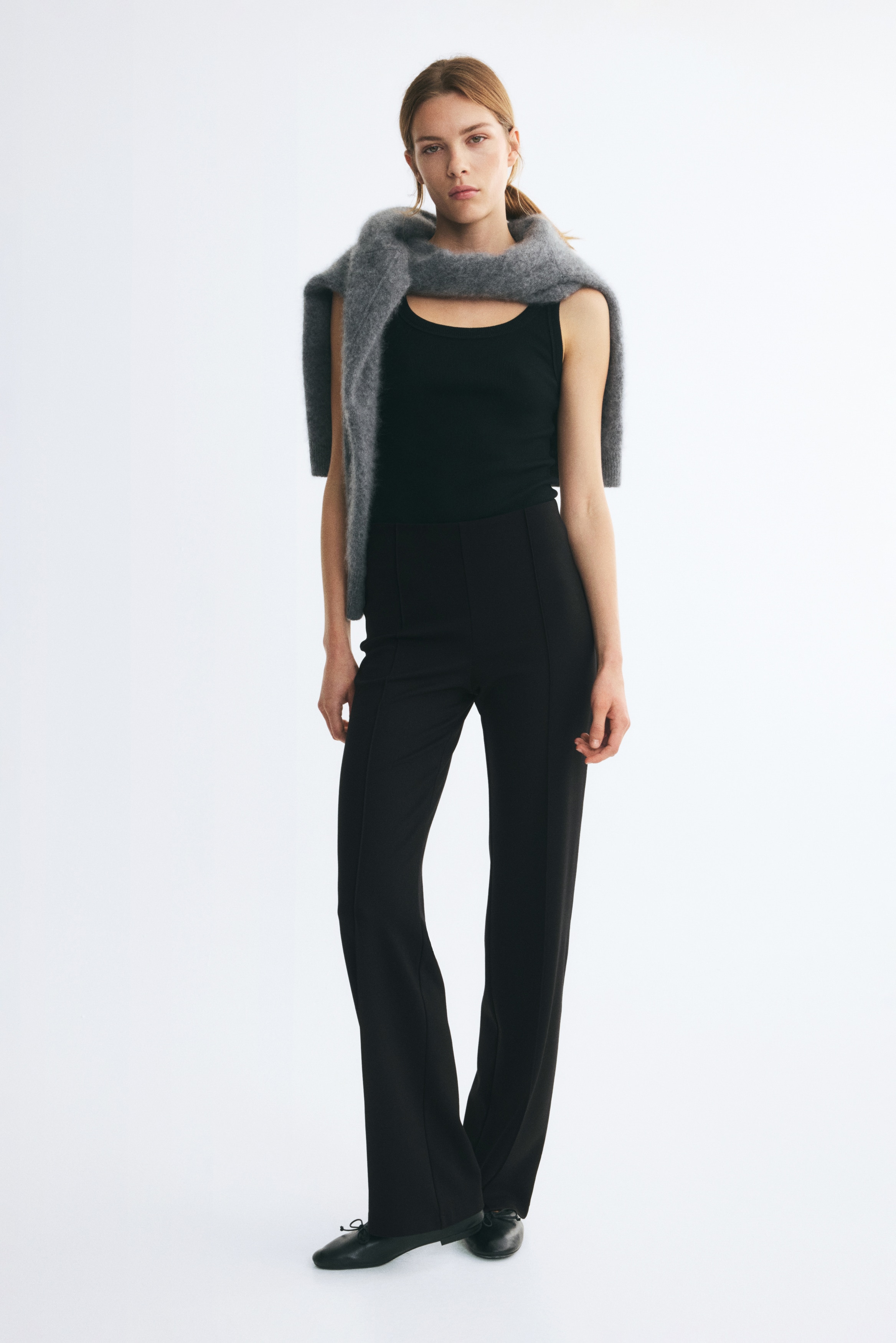 Schwarze Hose aus Ponte-di-Roma-Jersey, von vorne gezeigt, mit hoher Taille und verdecktem elastischem Bund. Das Design zeichnet sich durch eine schmale Passform aus, mit markanten BÃ¼gelfalten, die mittig an jedem Bein verlaufen und zum Saum hin in eine leichte ausgestellte Form Ã¼bergehen.